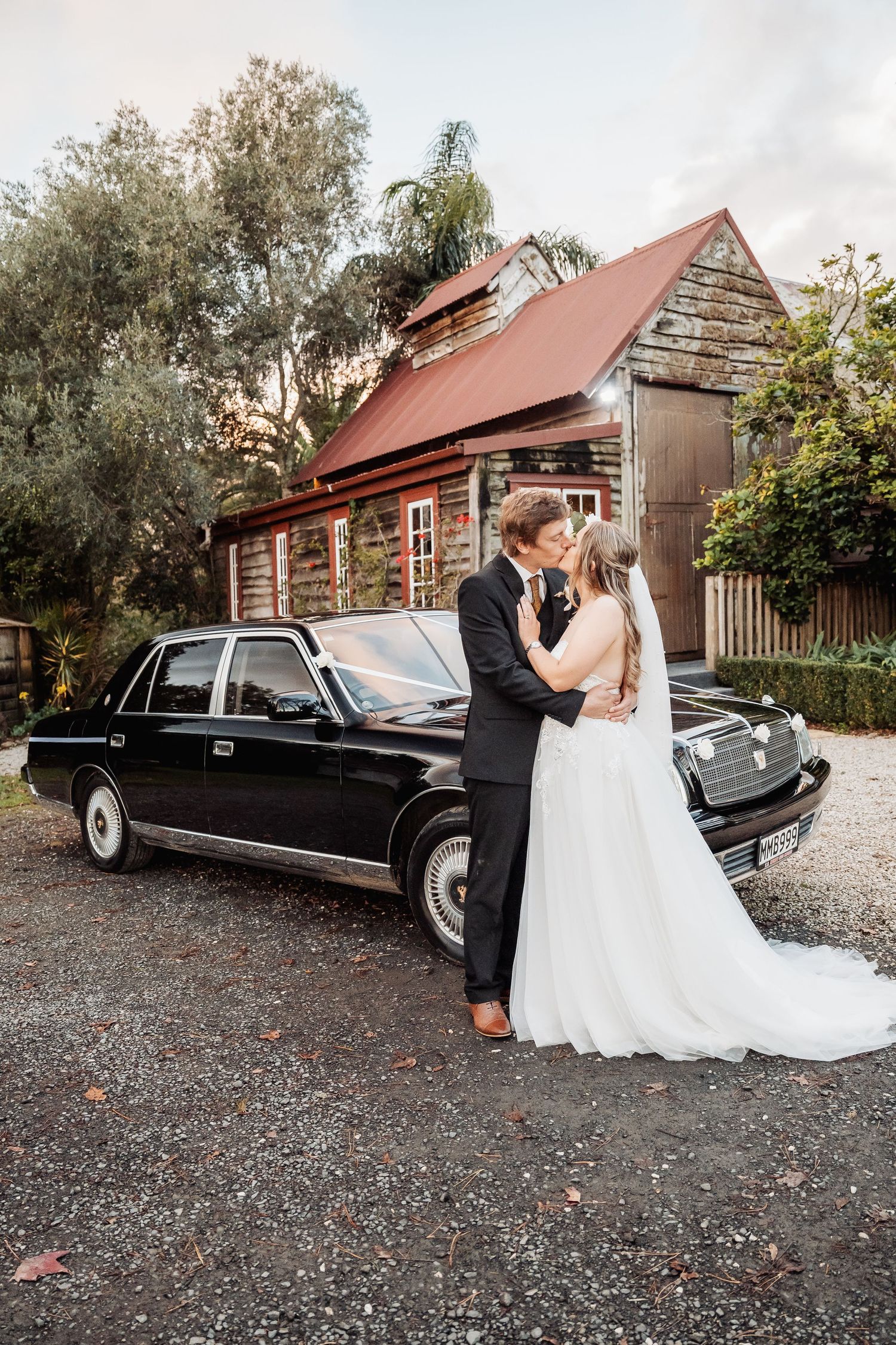A romantic wedding scene with vintage black car parked outside rustic log cabin.
