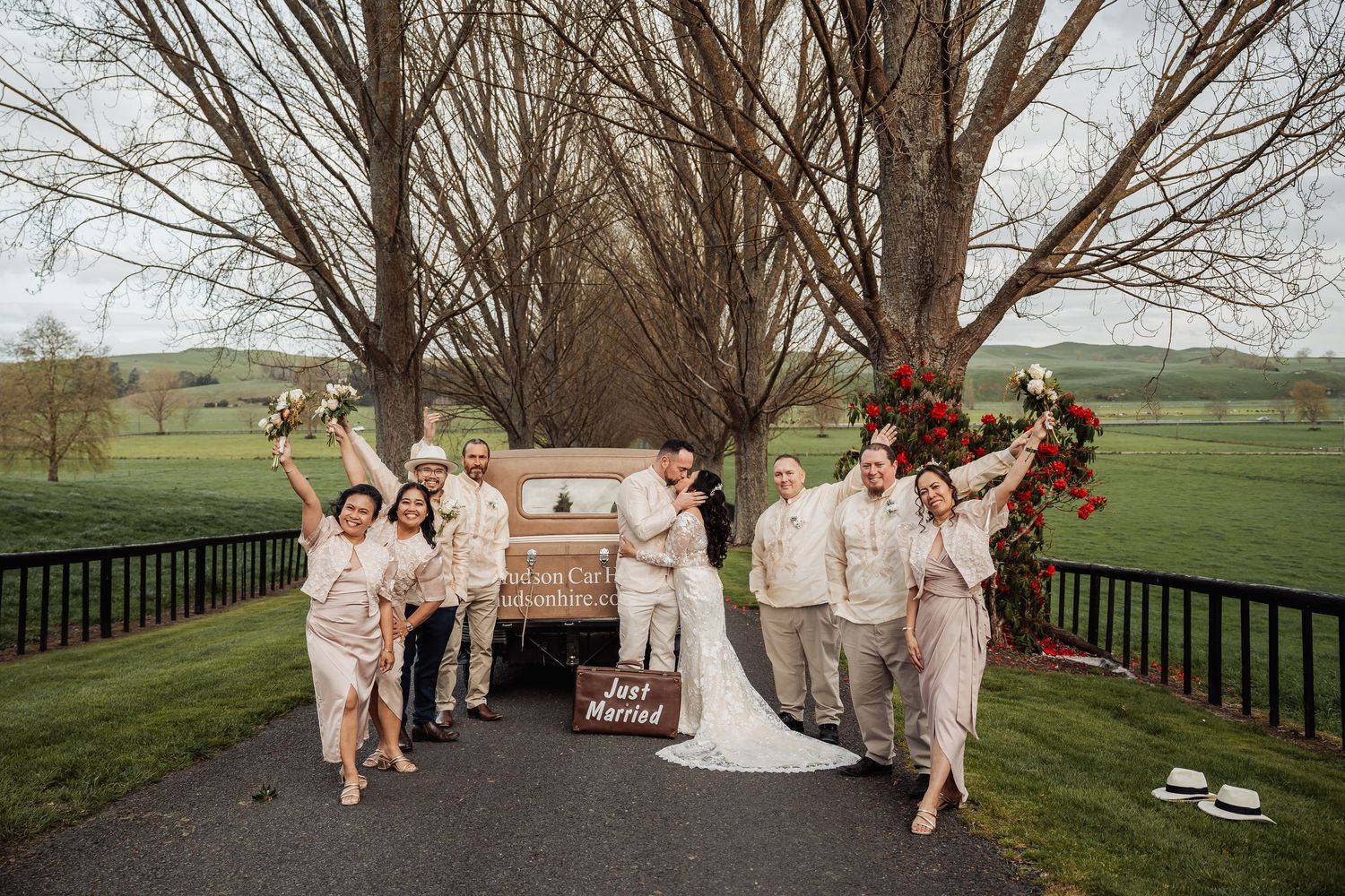 A couple shares intimate moments along a tree-lined pathway at a countryside venue.