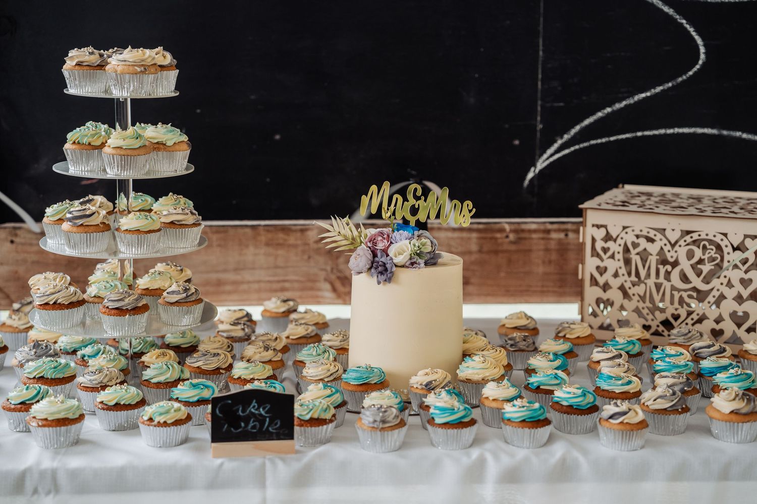 Wedding dessert table featuring a small cake with Mr and Mrs topper and cupcakes.