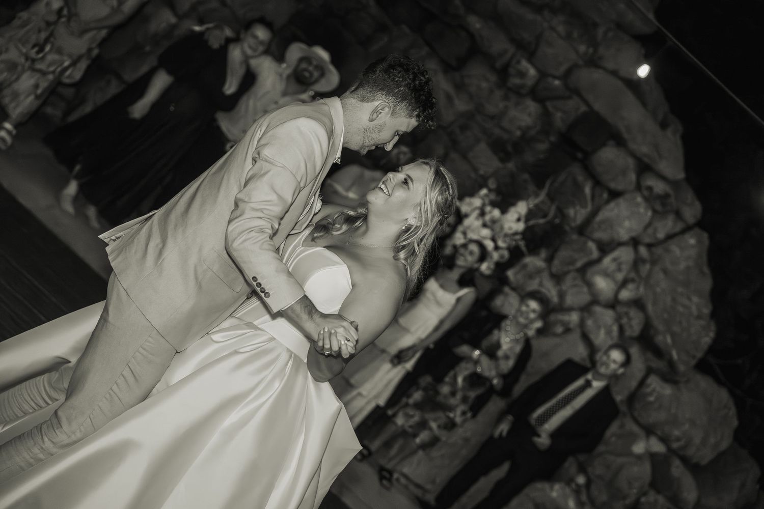 Black and white photo of bride and groom sharing a romantic dip dance at their wedding reception.