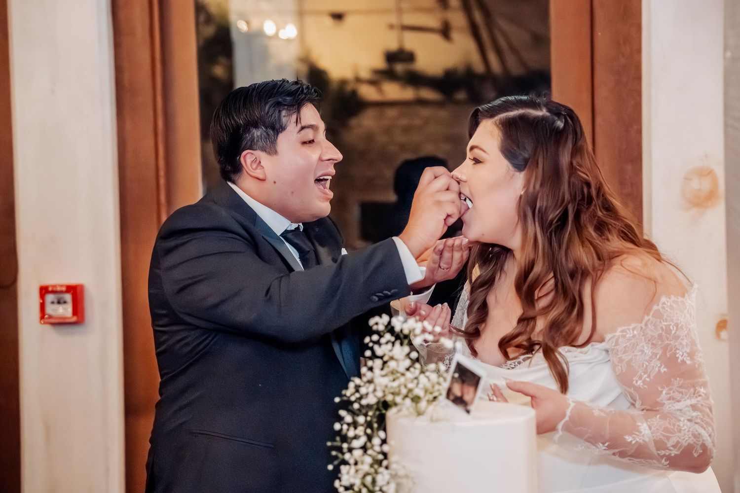 A couple embracing in a romantic moment during their wedding, surrounded by floral decorations and warm lighting.