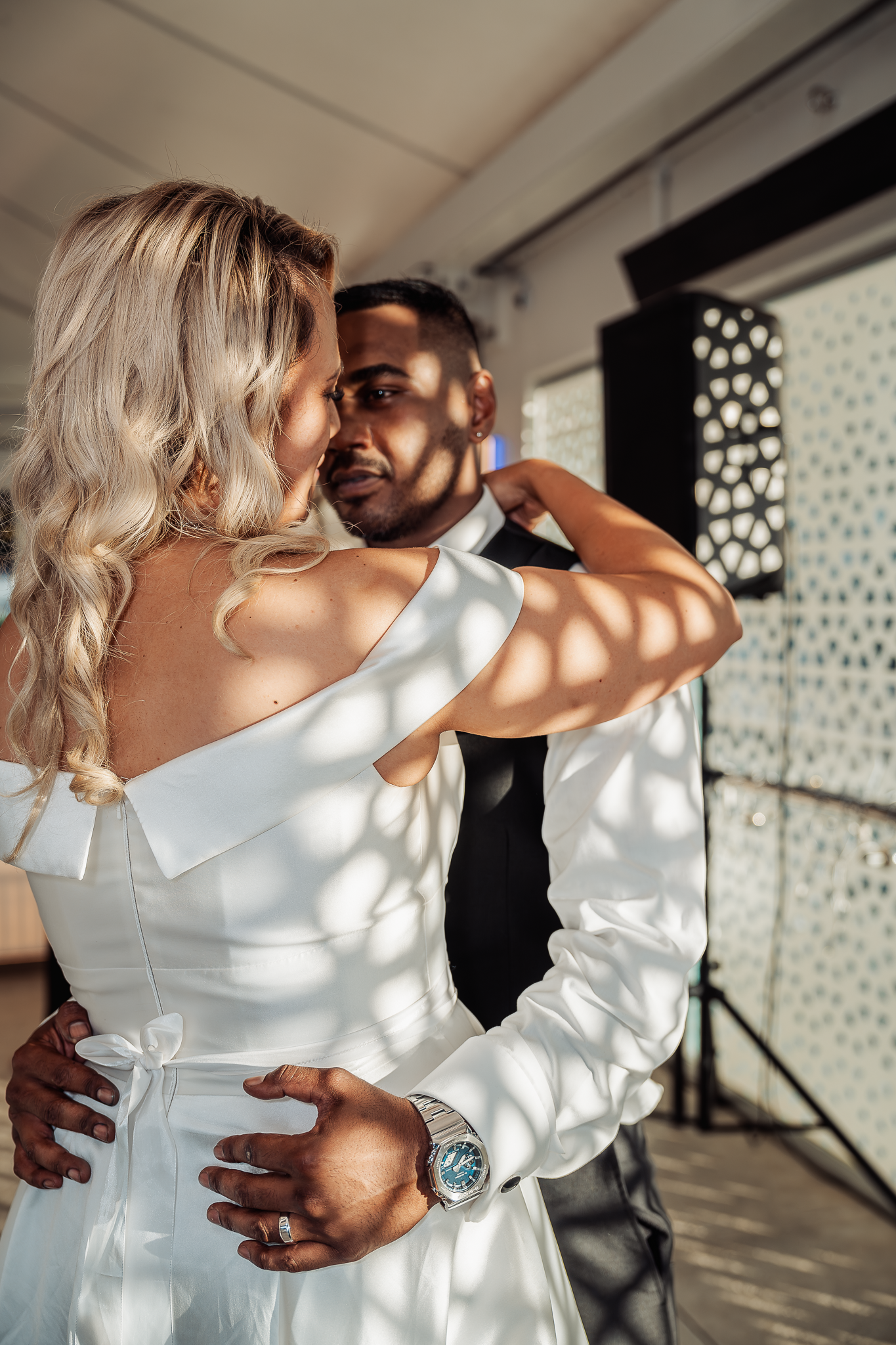 Couple embracing during wedding dance with dramatic spotted lighting effects.