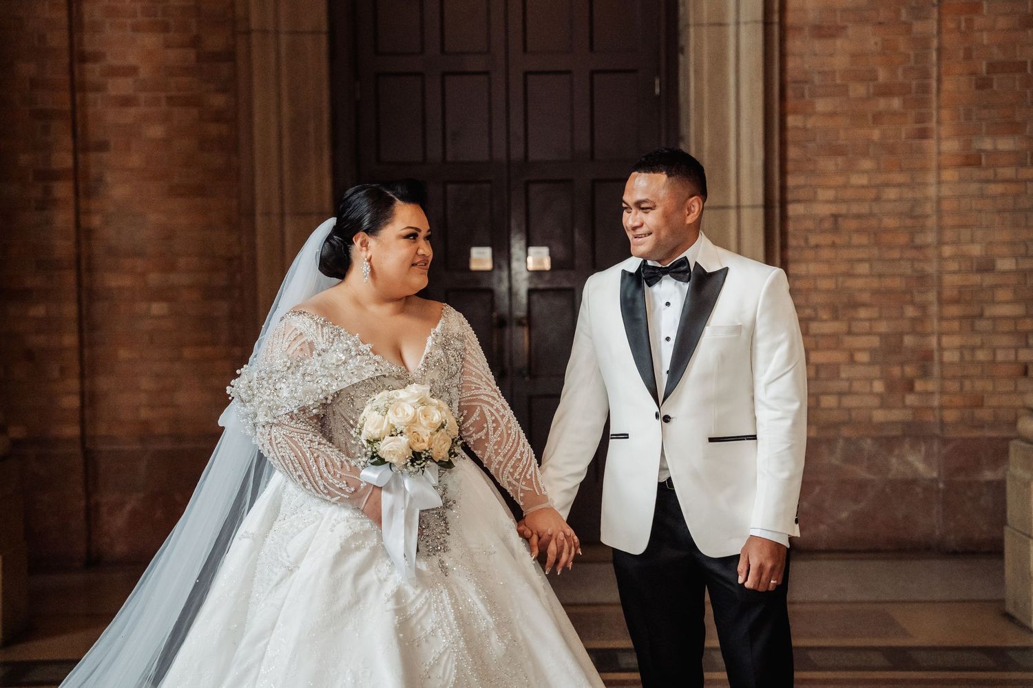 Bride and groom share an intimate dance together in a grand brick-walled venue.