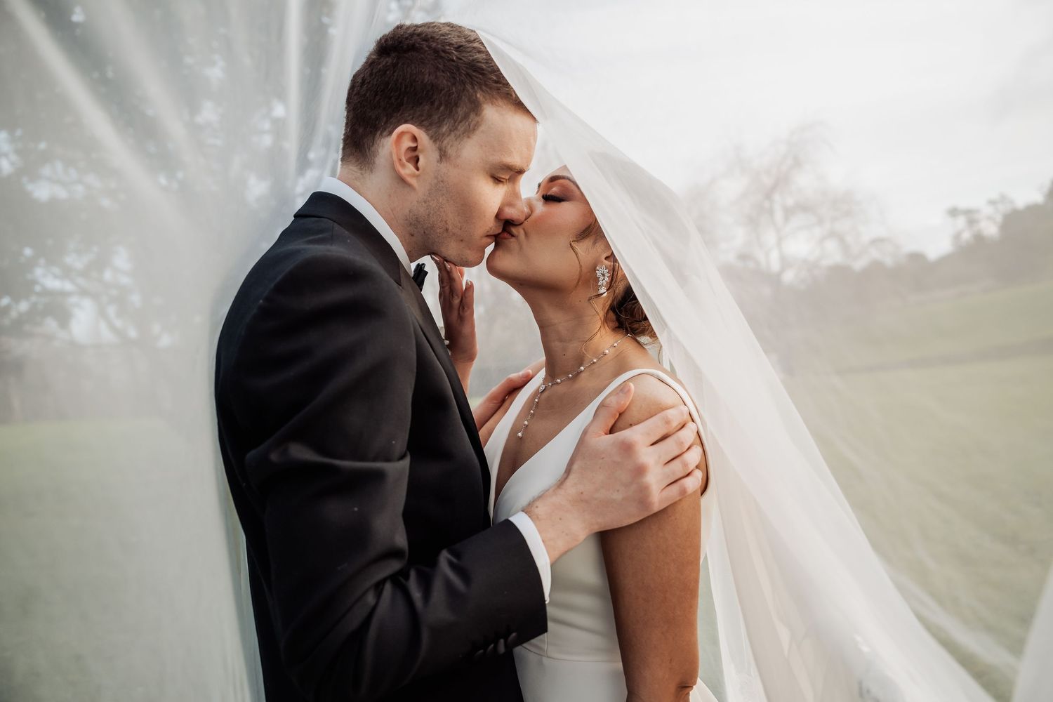 Romantic wedding couple sharing an intimate moment in dreamy outdoor setting.