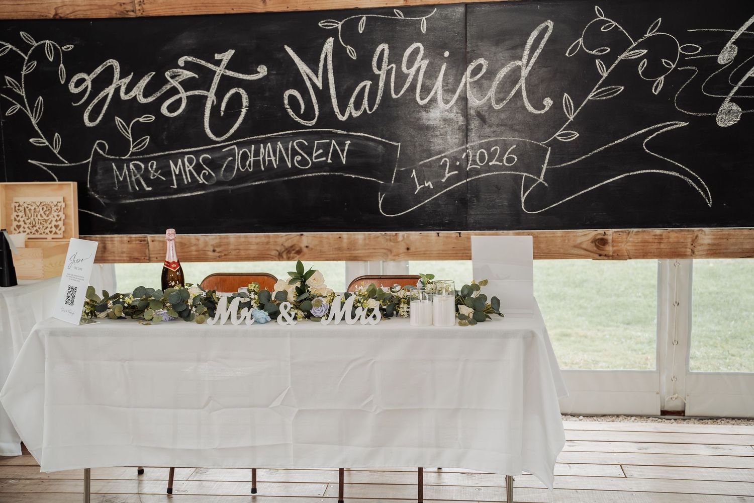 Just Married chalkboard sign decorates the Mr and Mrs Johansen sweetheart table at wedding reception.
