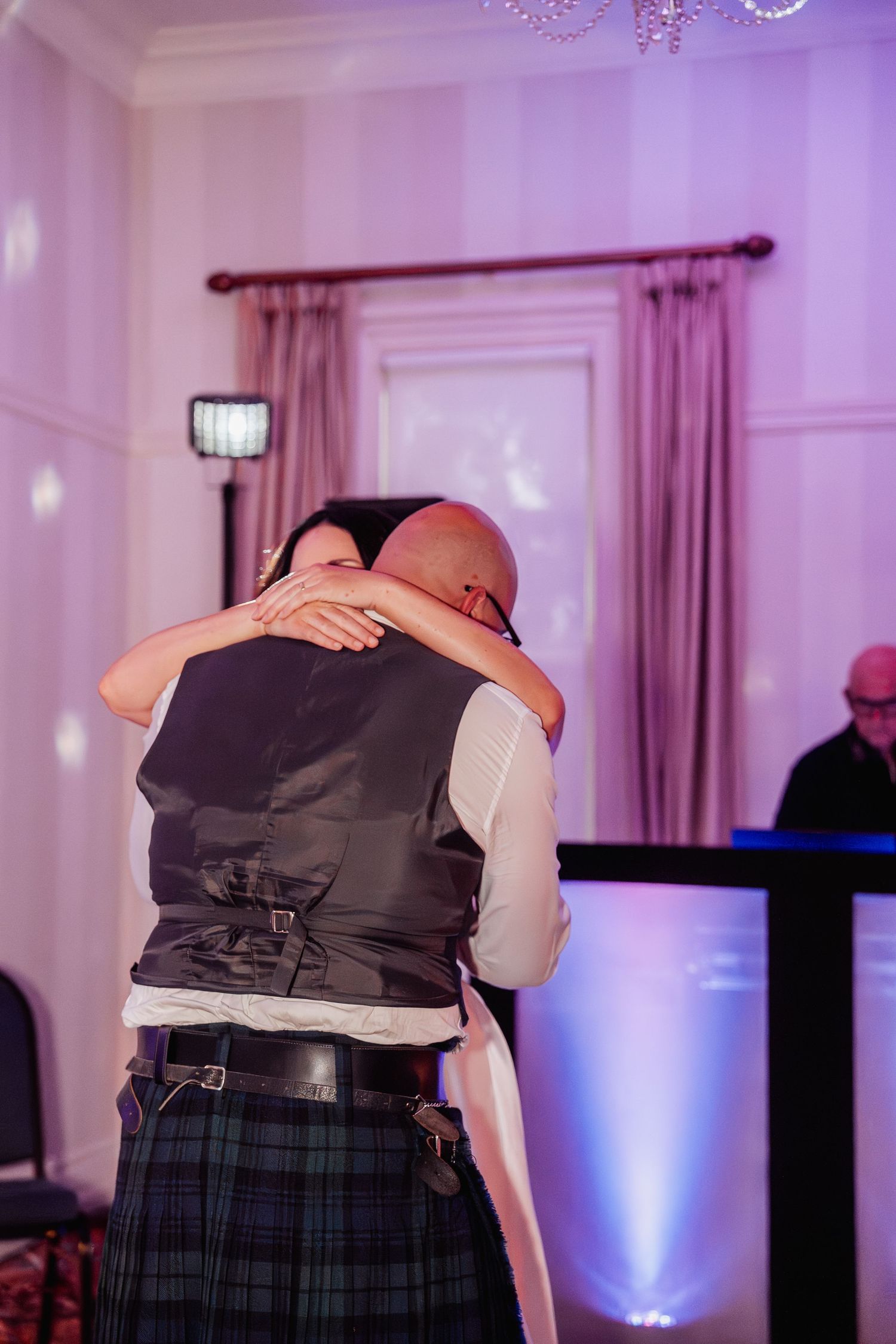 A bride and groom share a tender embrace on the dance floor during their wedding reception.