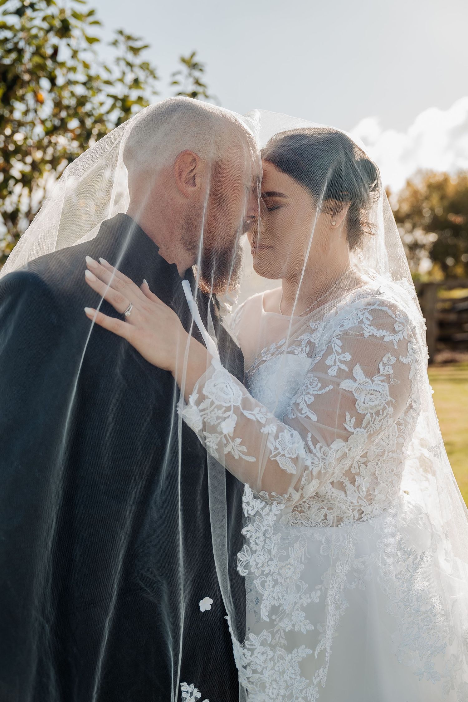 A tender moment between newlyweds as they embrace outdoors on their sun-lit autumn wedding day.