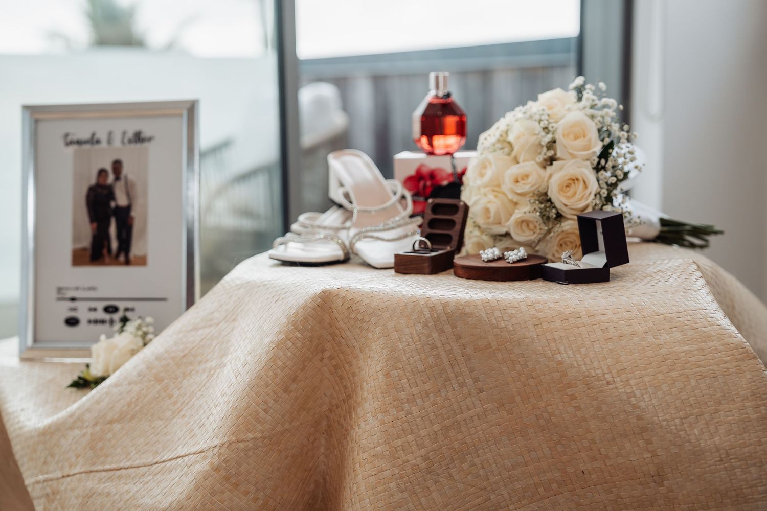 A long rustic wedding table decorated with flowers, candles and white linens in a sunlit reception space.