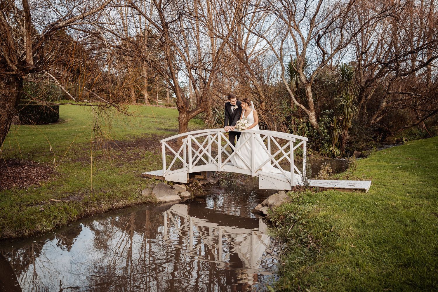 Rustic garden path with wooden bridge and bare trees creating a romantic wedding setting.