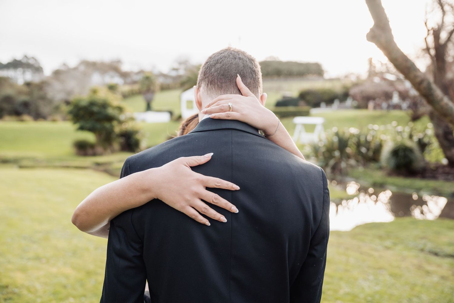 A couple shares an intimate moment while embracing on a lush green golf course on their wedding day.