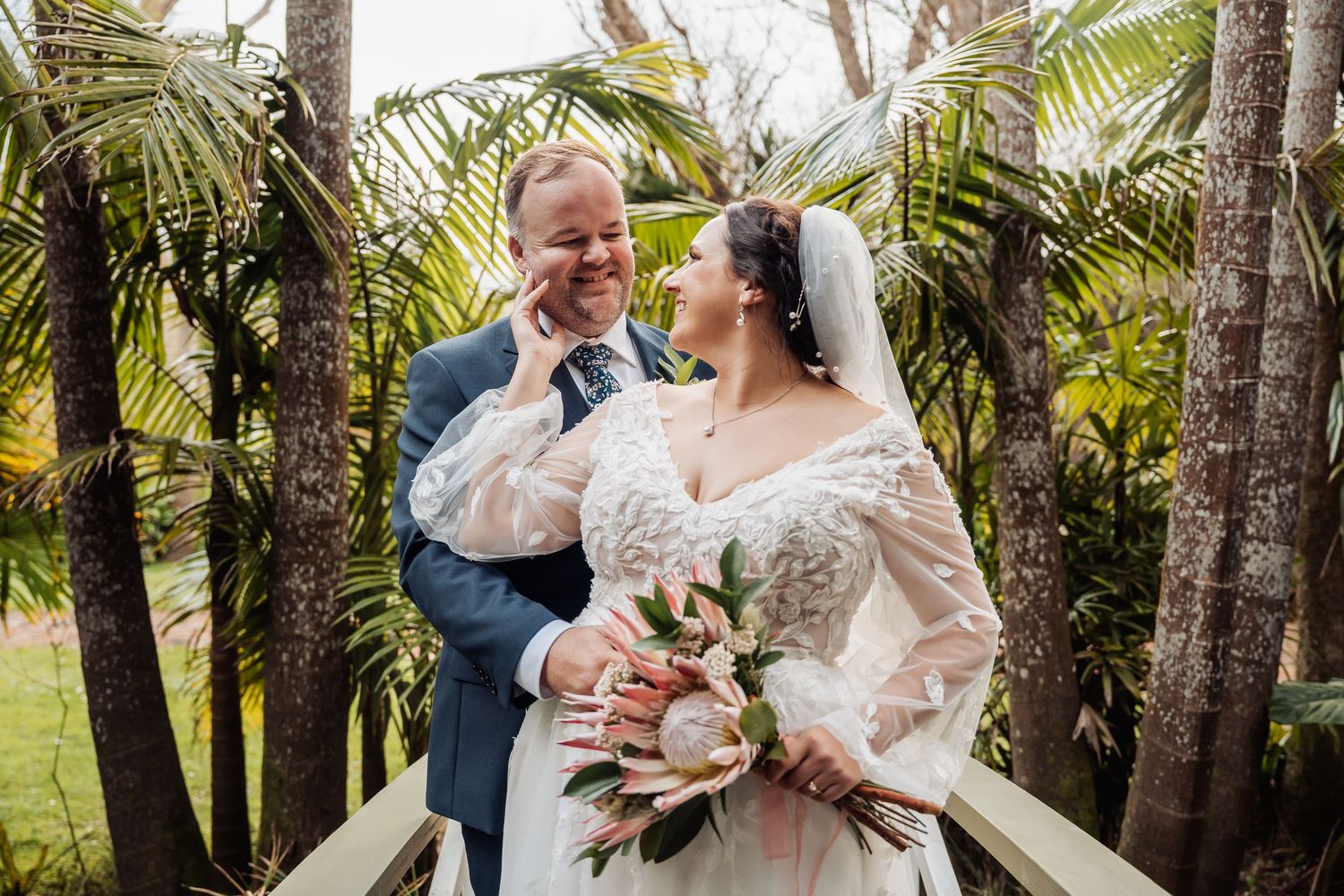 Wedding couple sharing an intimate moment among palm trees and tropical greenery.