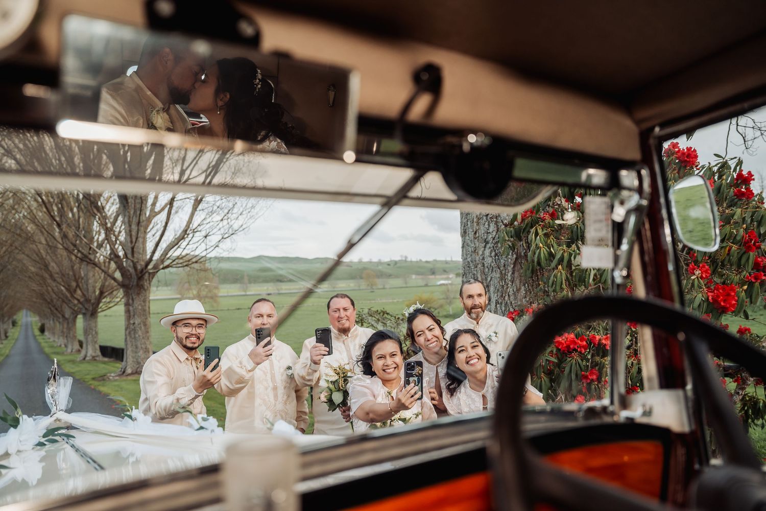 Vintage car parked along a tree-lined path at a rustic countryside wedding venue.