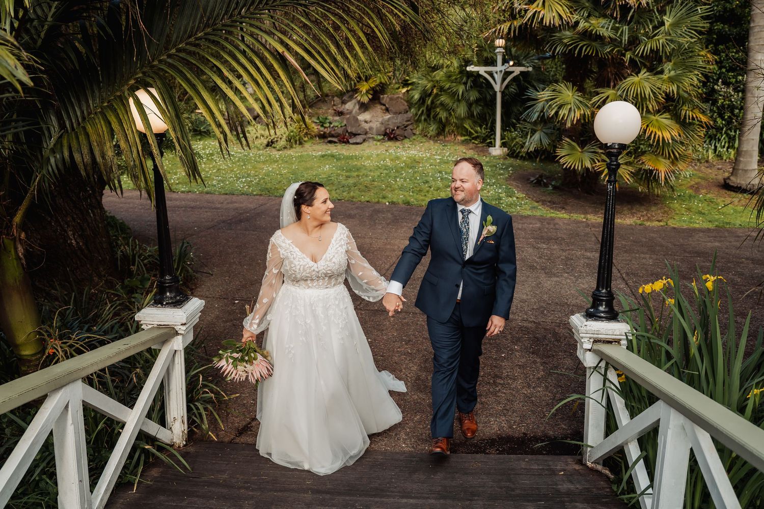 A sequence of romantic wedding portraits captured on a wooden bridge surrounded by lush tropical landscaping.