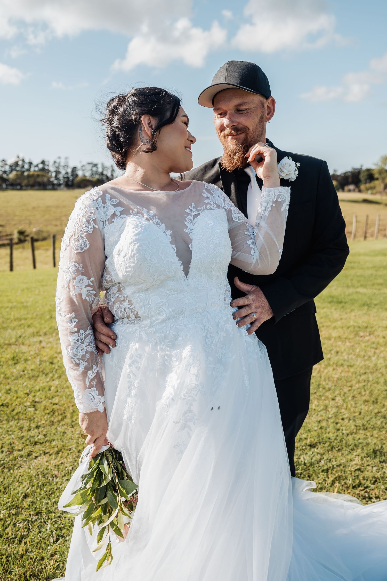 A candid romantic moment between newlyweds in a rustic outdoor setting.