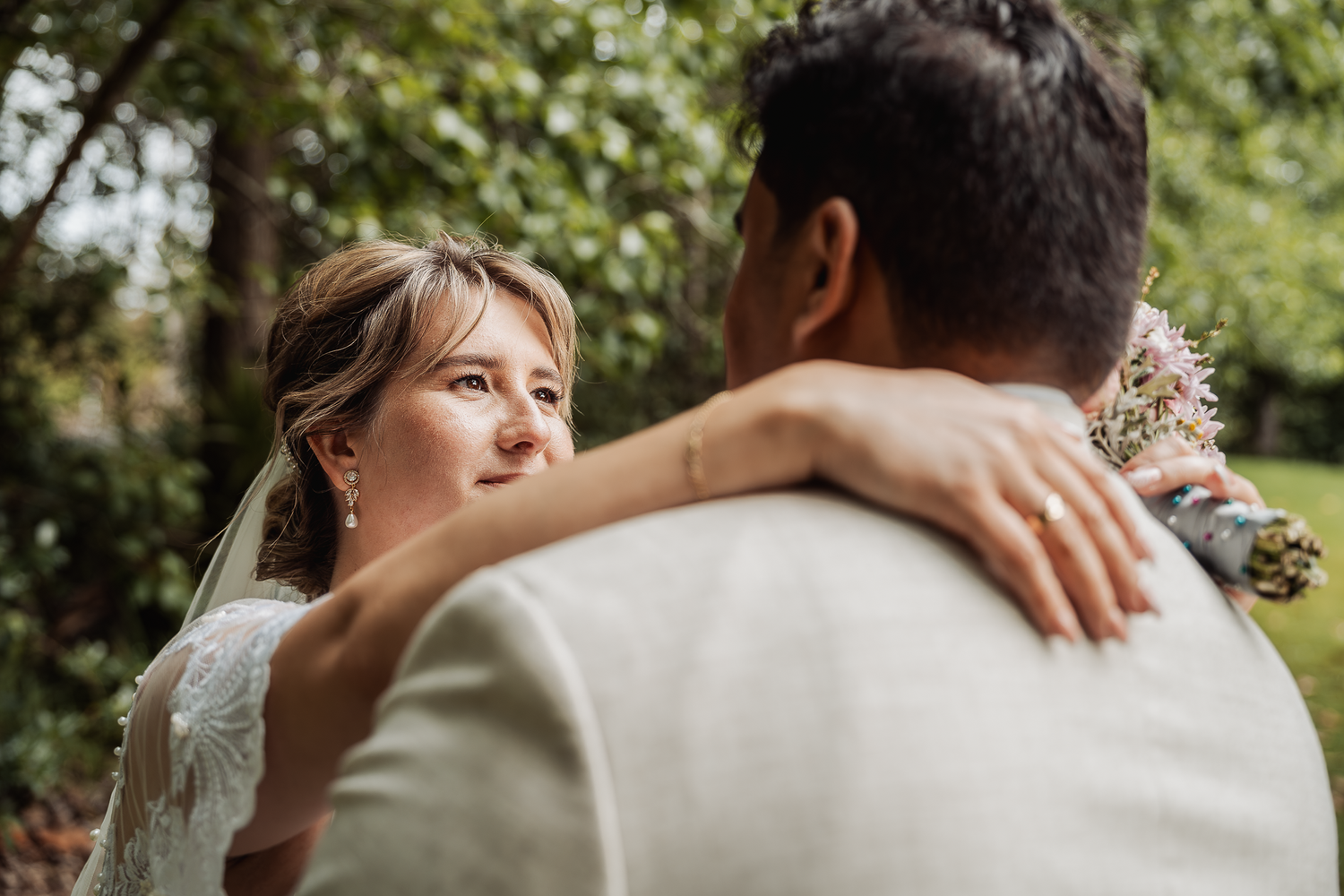 Intimate embrace captured during outdoor wedding photoshoot in garden setting.