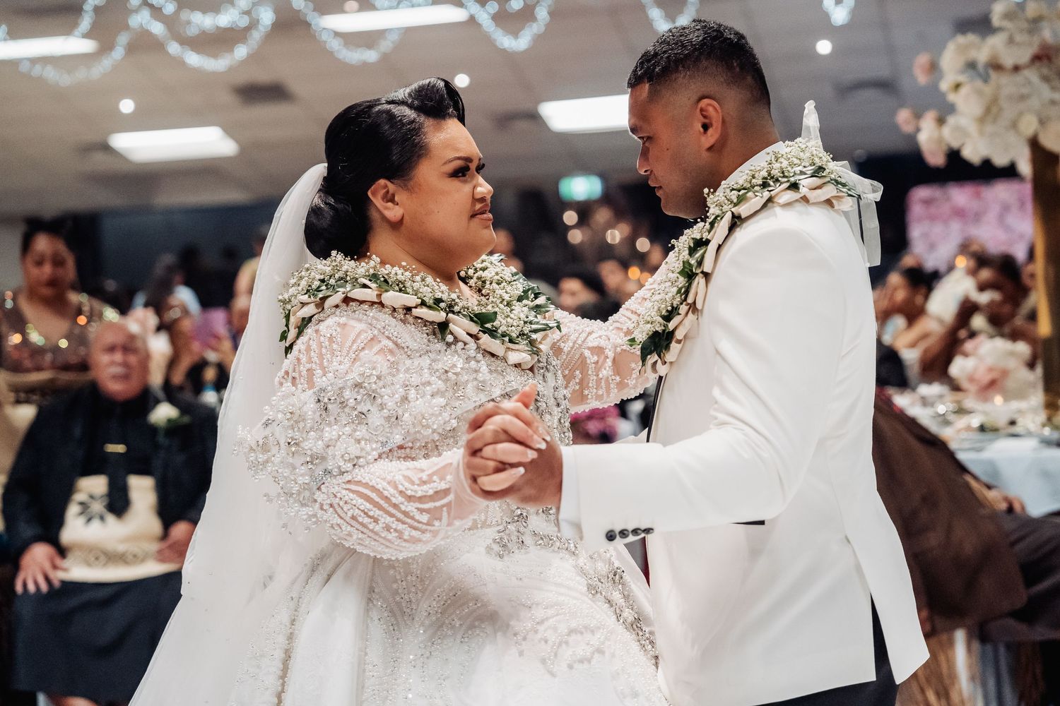 Wedding couple shares first dance surrounded by string lights and elegant decor.