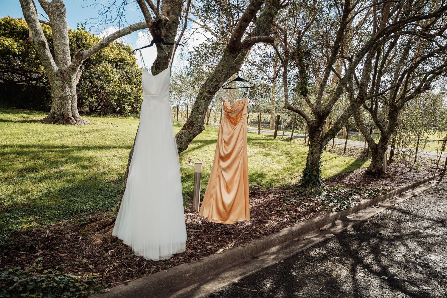 A couple stands in a romantic garden setting with white and blush florals around them.
