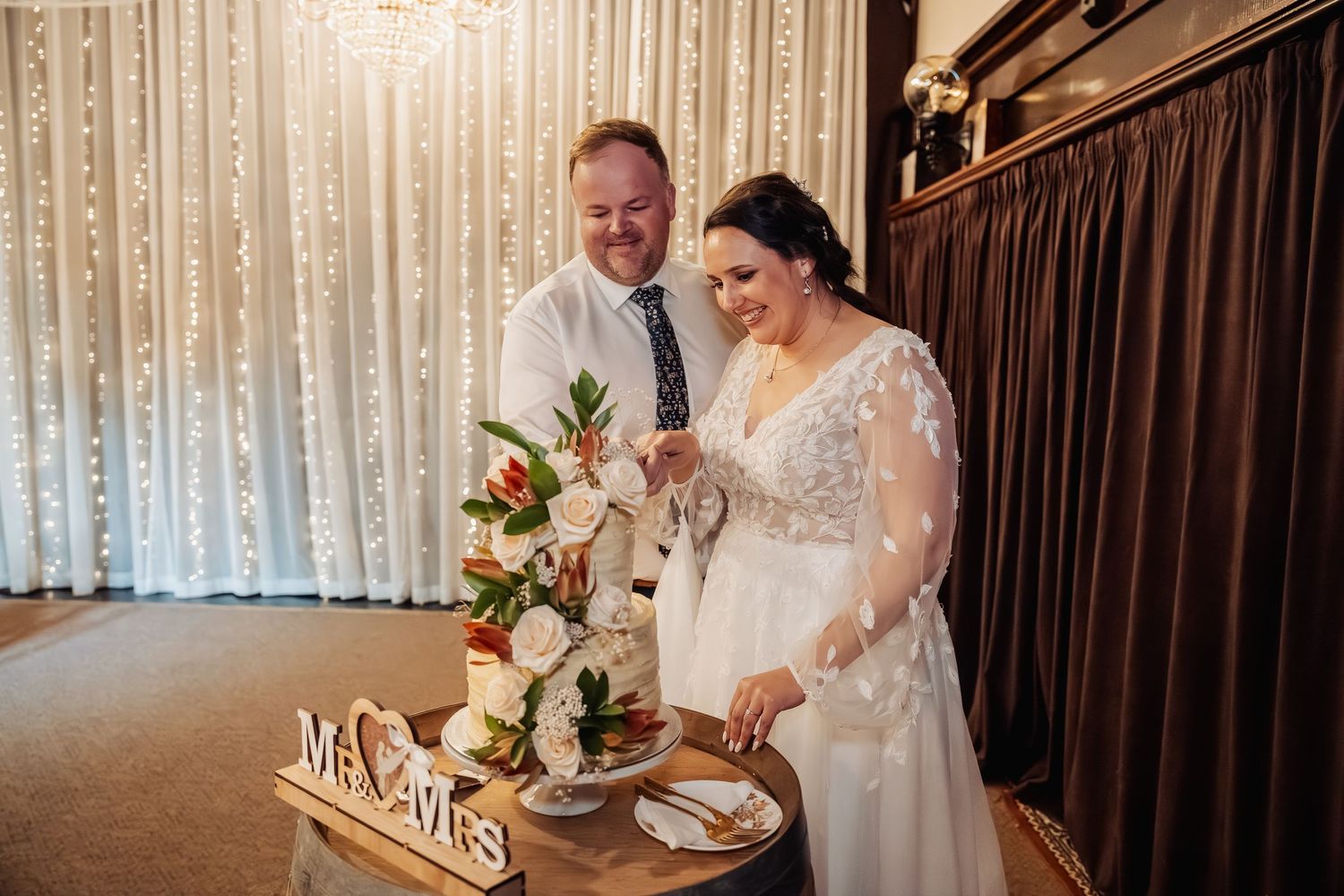 Newlyweds sign their marriage license at an elegant reception venue with white drapes.