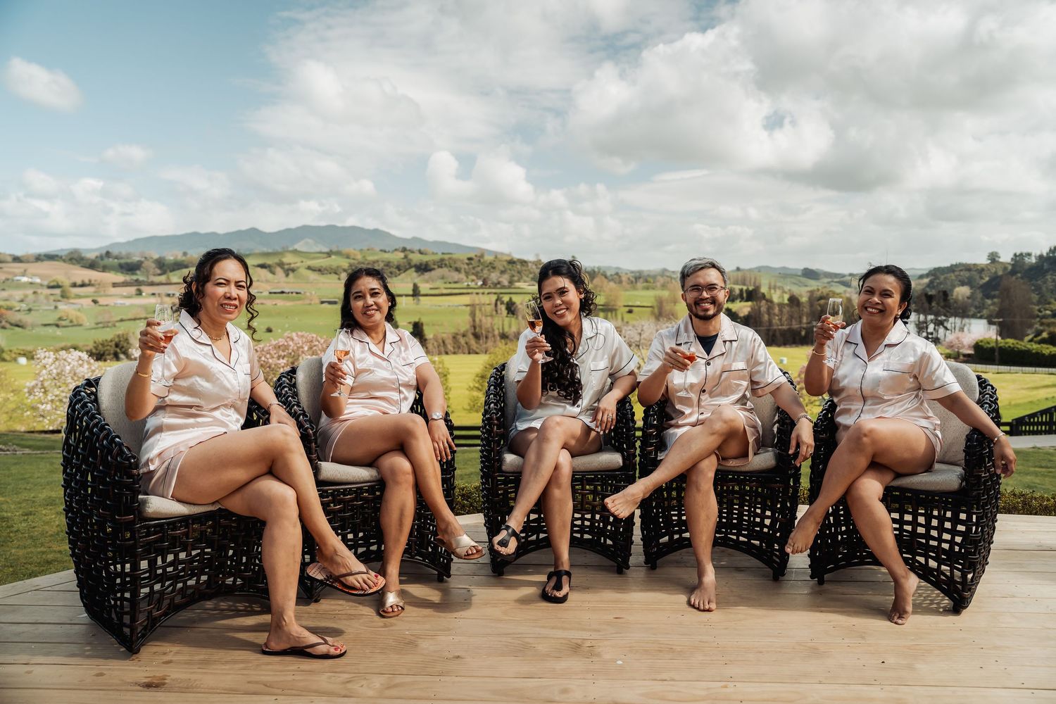 Group of people relaxing outdoors on black chairs with scenic mountain views in the background.