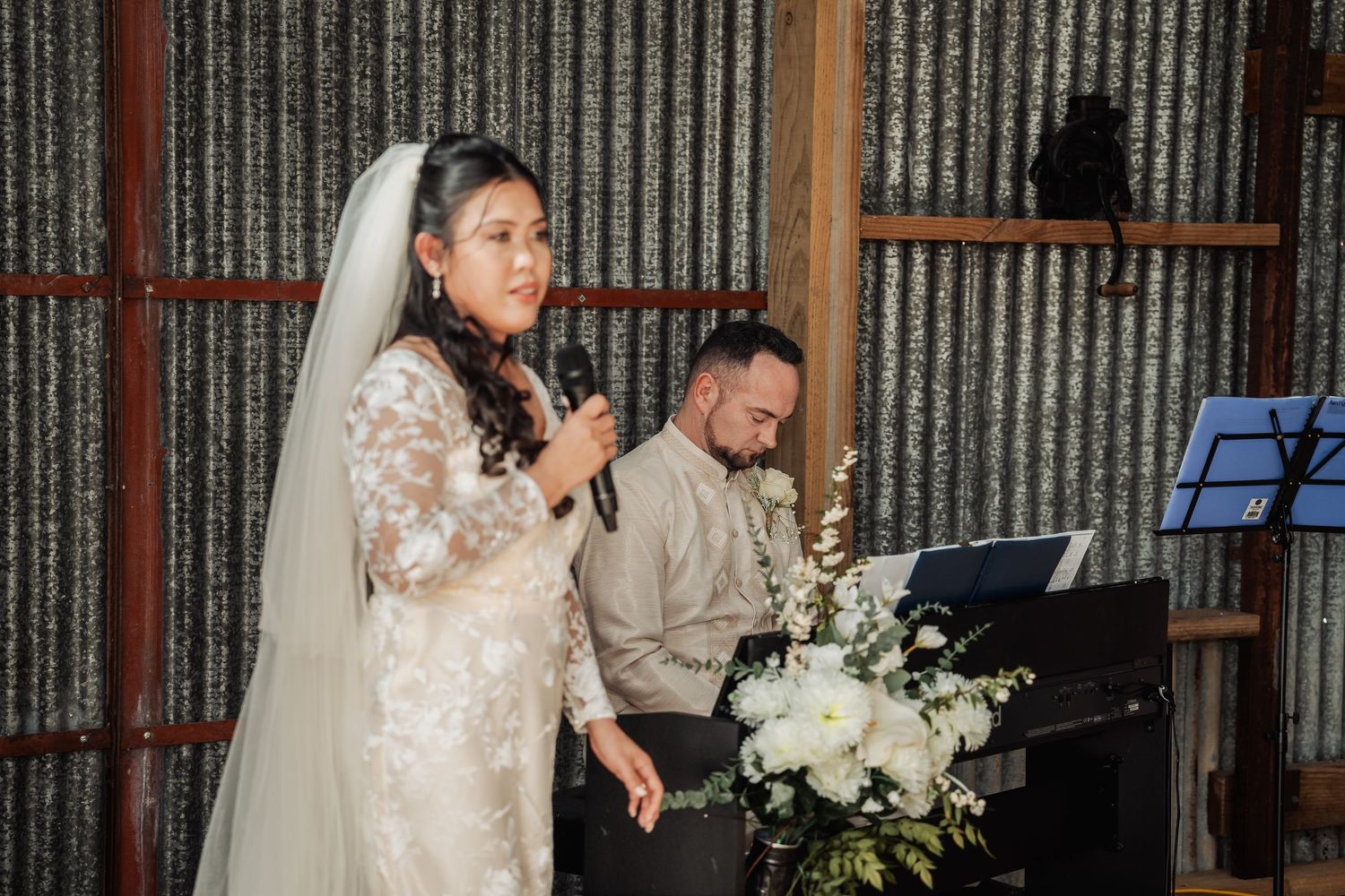 A wedding ceremony moment captured inside a rustic barn with corrugated metal walls.