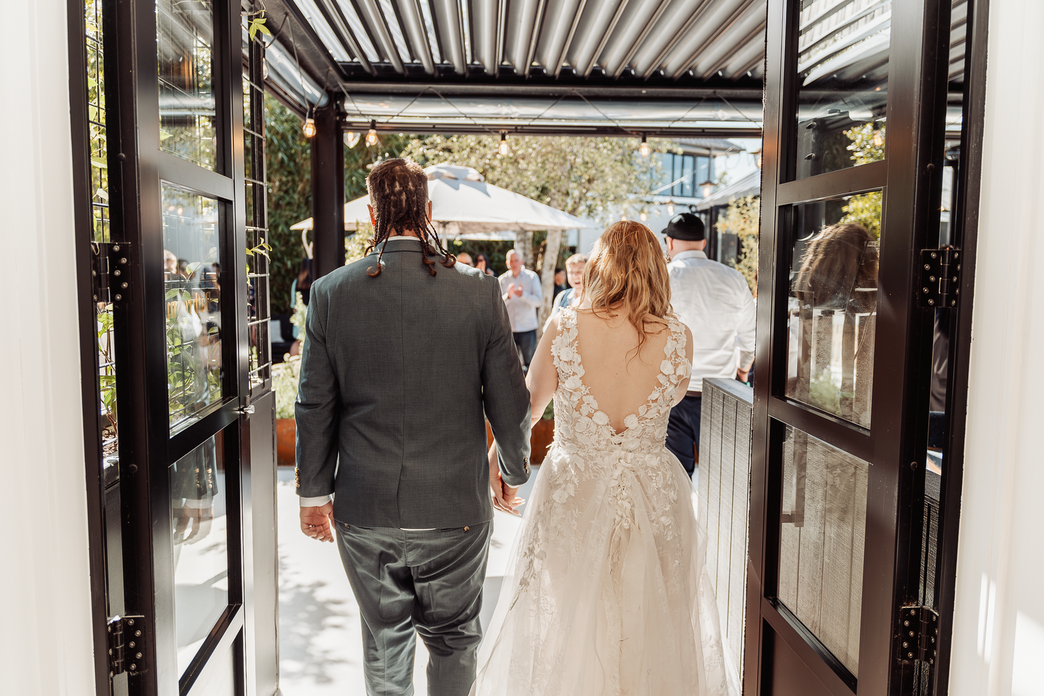 Newlyweds walk through a modern covered walkway after their wedding ceremony.