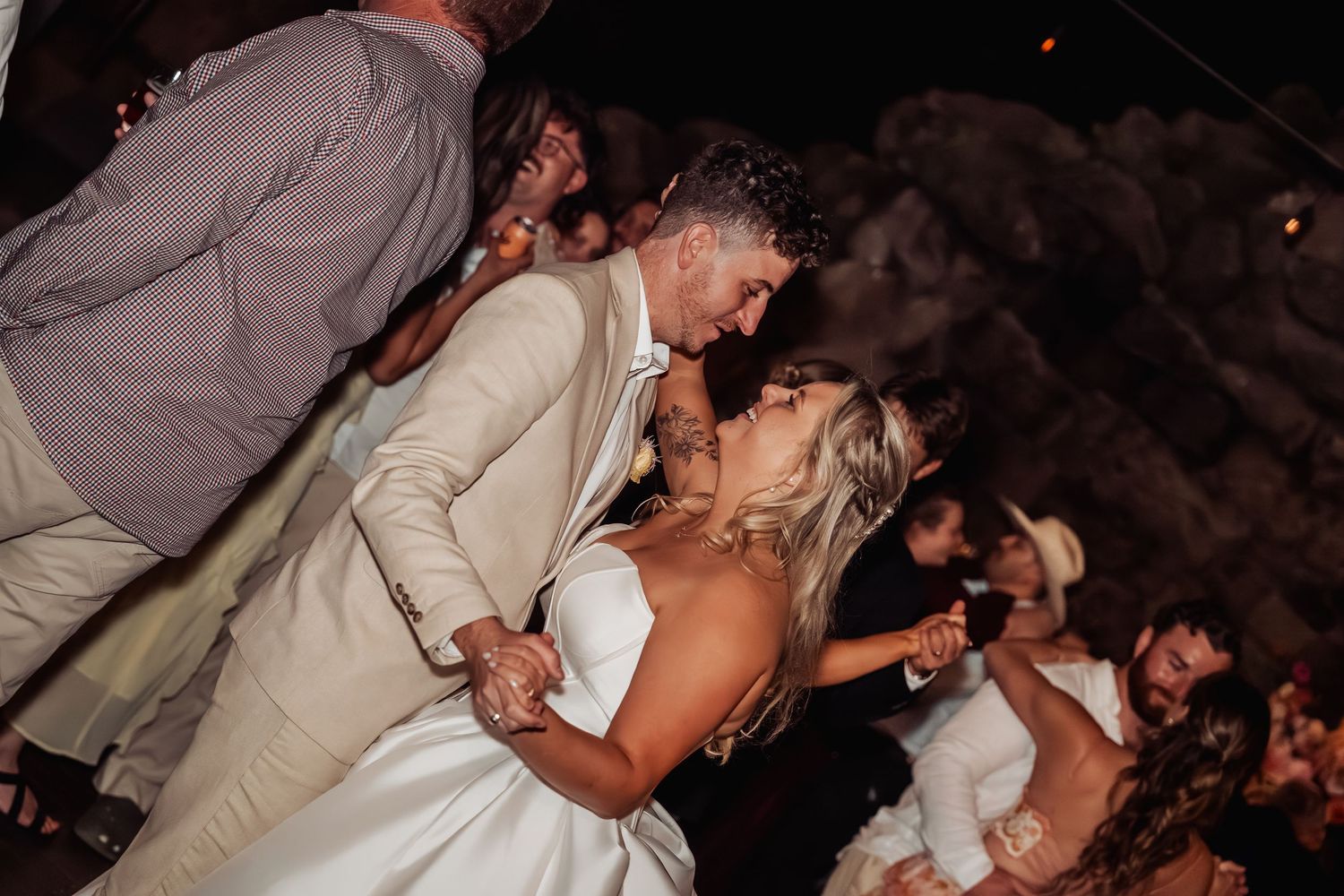 Bride and groom share a romantic kiss while dancing closely at their wedding reception.