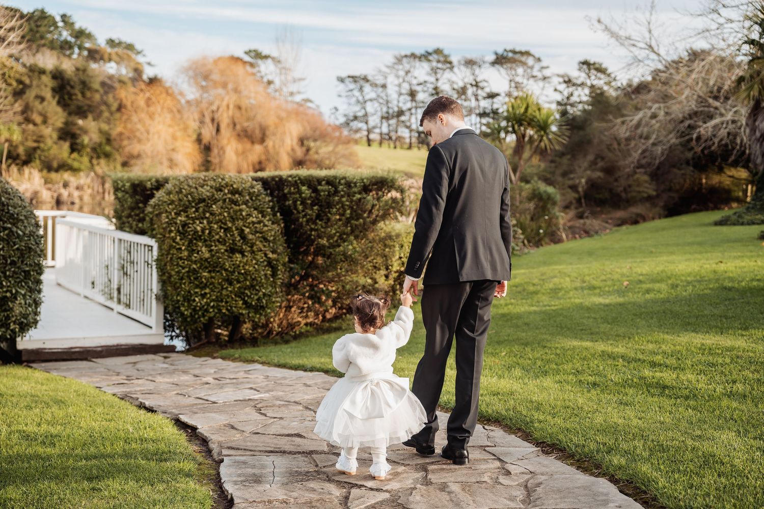 Wedding party walking along a stone path surrounded by scenic coastal landscape.