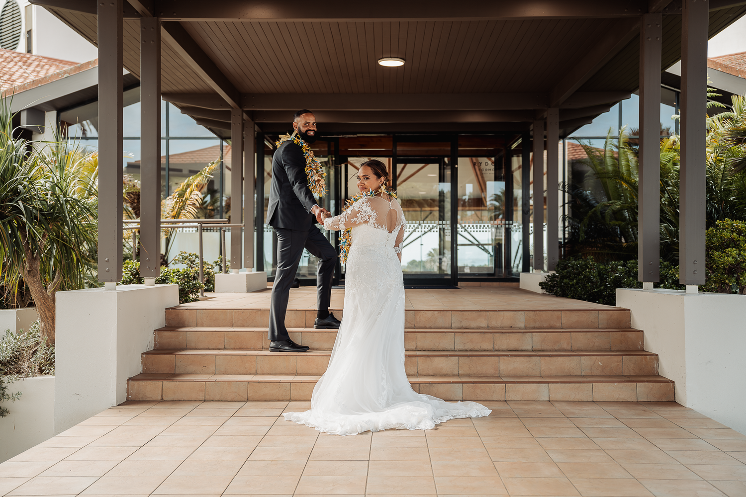 Elegant couple poses on modern architectural steps with covered walkway.