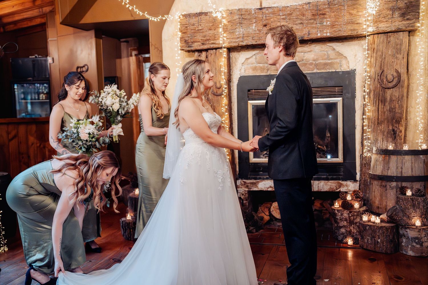 A wedding ceremony taking place in a rustic interior with exposed brick walls and string lights overhead.