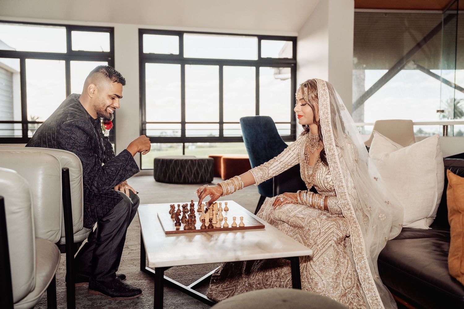 Wedding couple dancing and celebrating in modern venue with large windows.