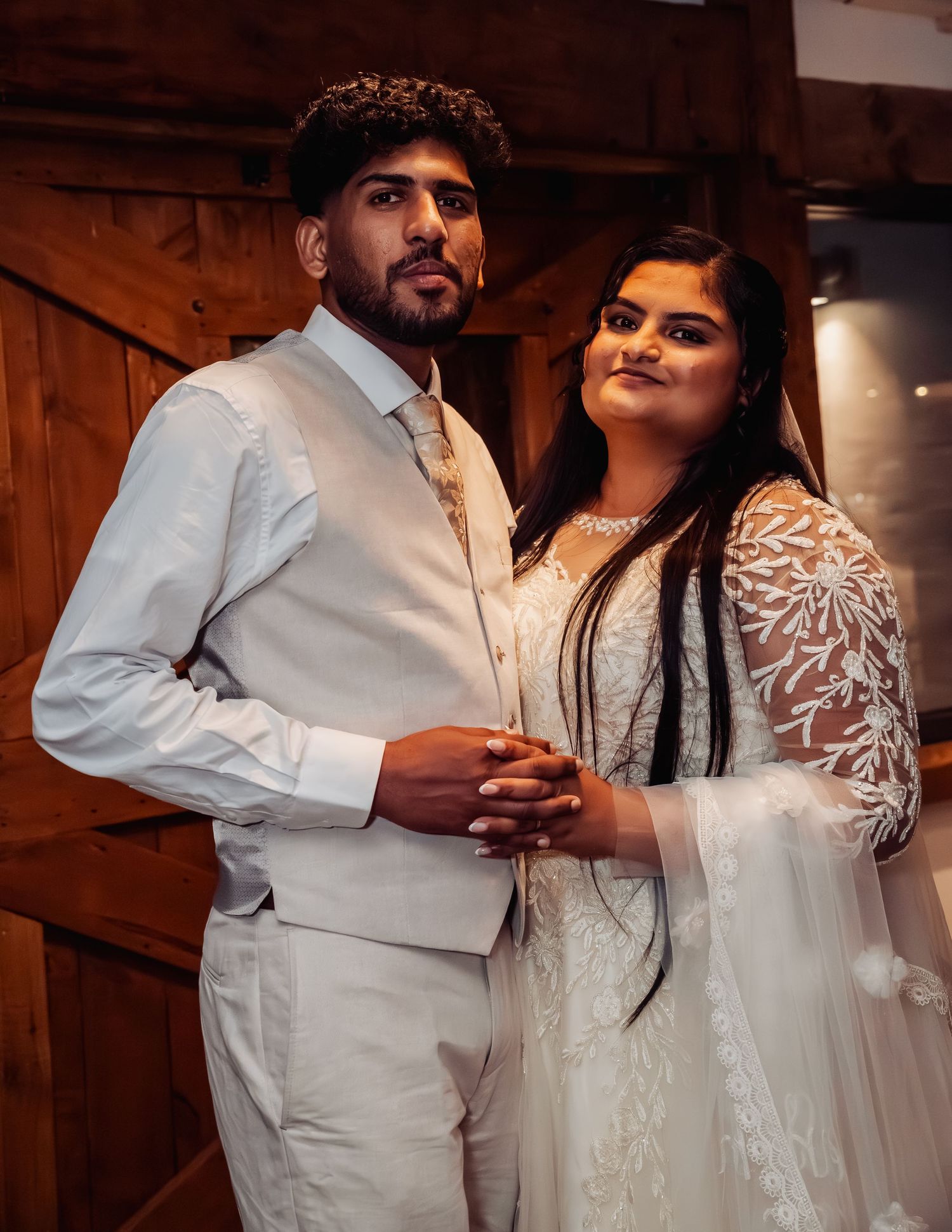 Bride and groom posing elegantly in rustic barn setting after wedding ceremony.