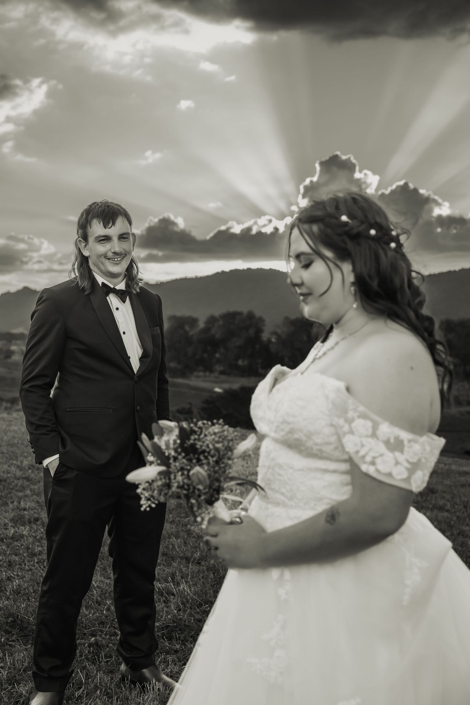 Bride and groom portrait with dramatic sunrays at golden hour in black and white.