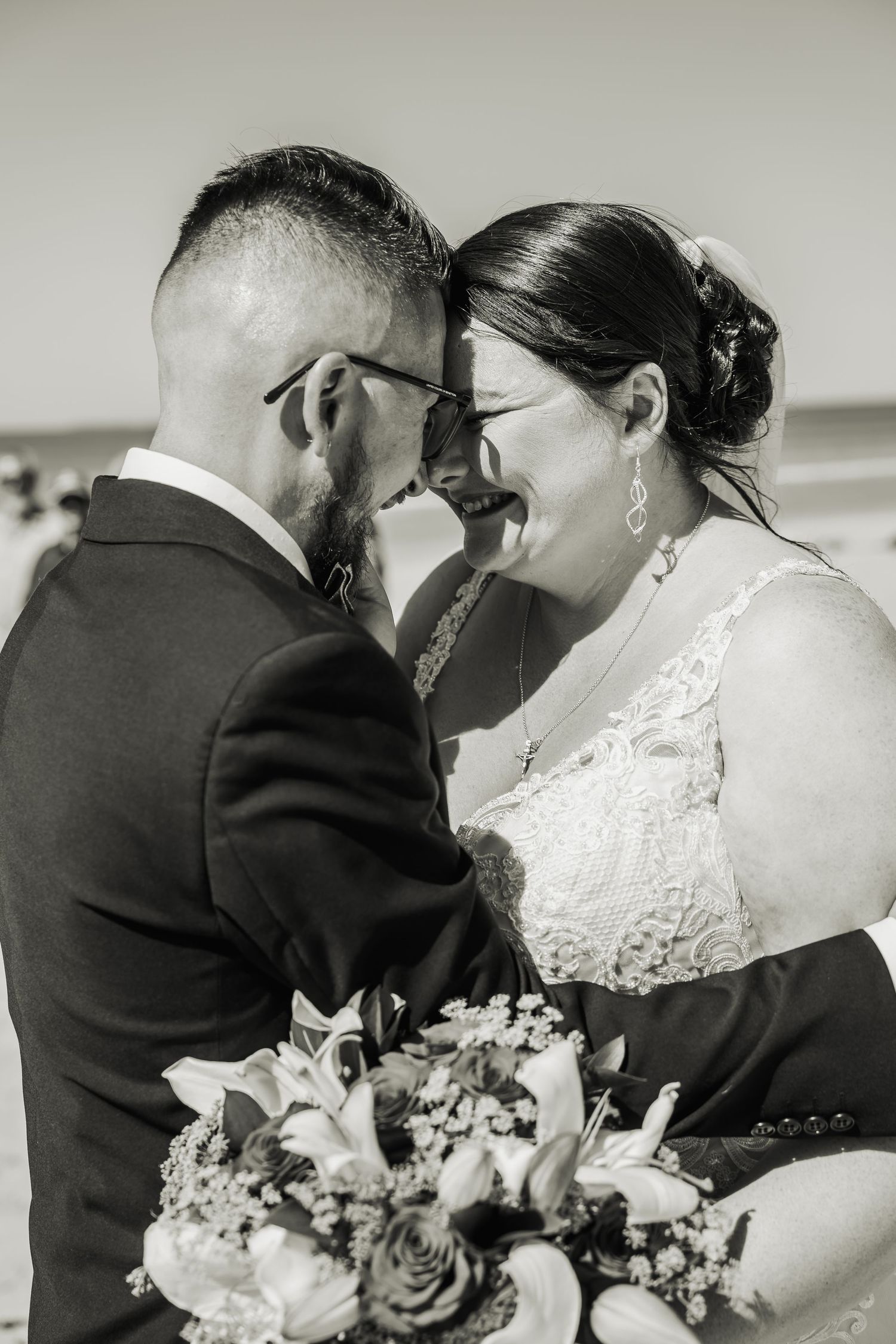 Black and white photo of a joyful couple sharing an intimate moment on their wedding day.