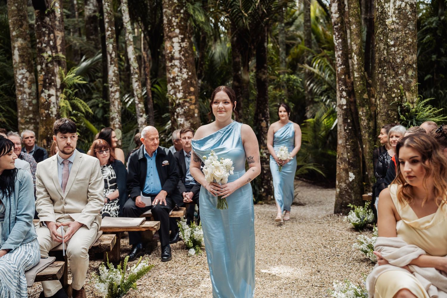 Wedding party poses together in a lush forest setting with natural lighting.
