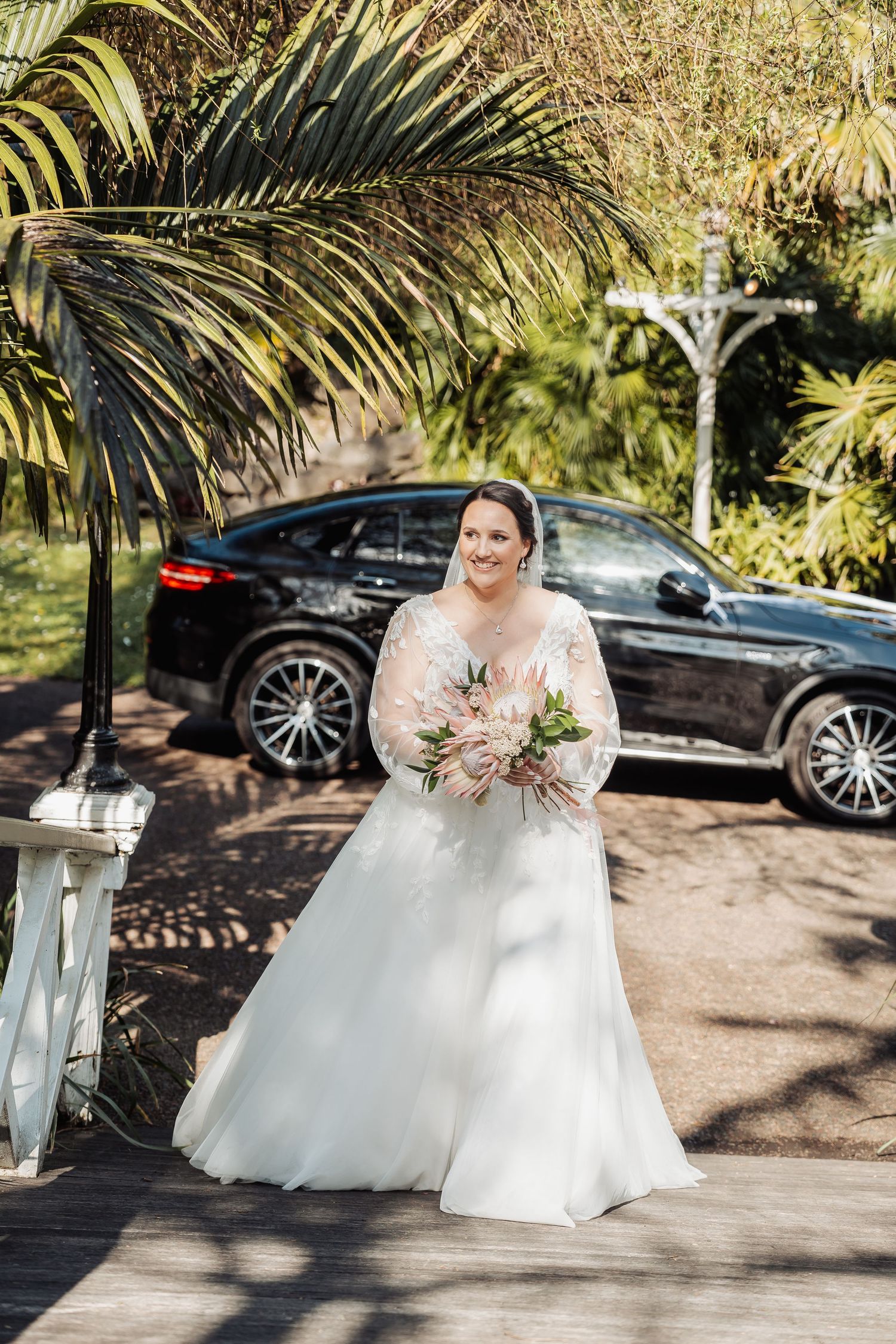 A series of wedding photos showing a bride in a white gown posing near palm trees and a black luxury car.