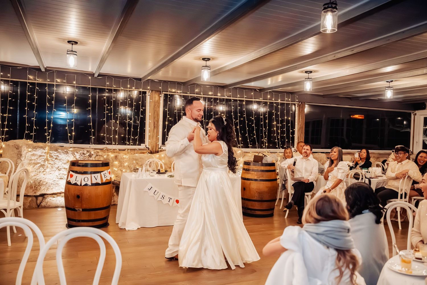 Reception venue decorated with hanging lights and white linens for evening celebration.