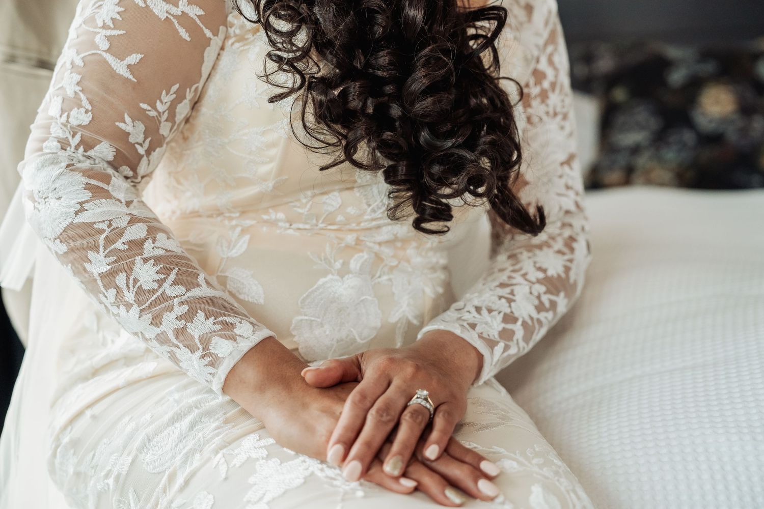 Delicate lace details of a wedding dress shown in close-up against natural lighting.