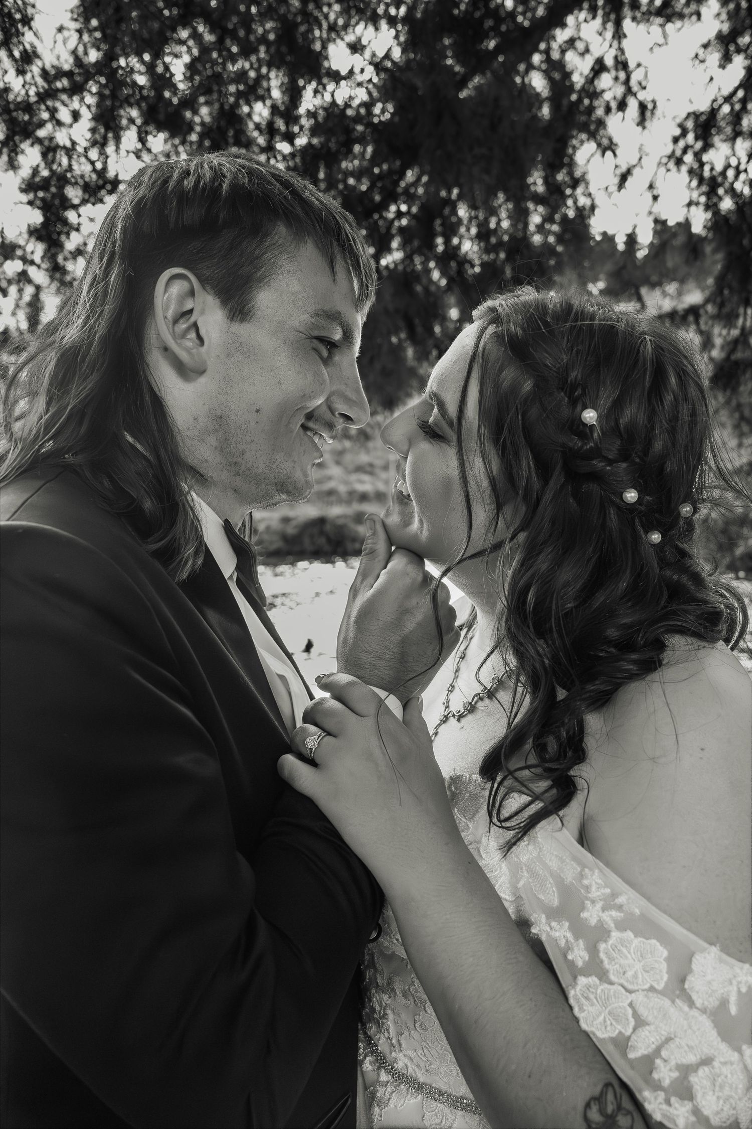 Black and white portrait of bride and groom sharing an intimate moment about to kiss outdoors.
