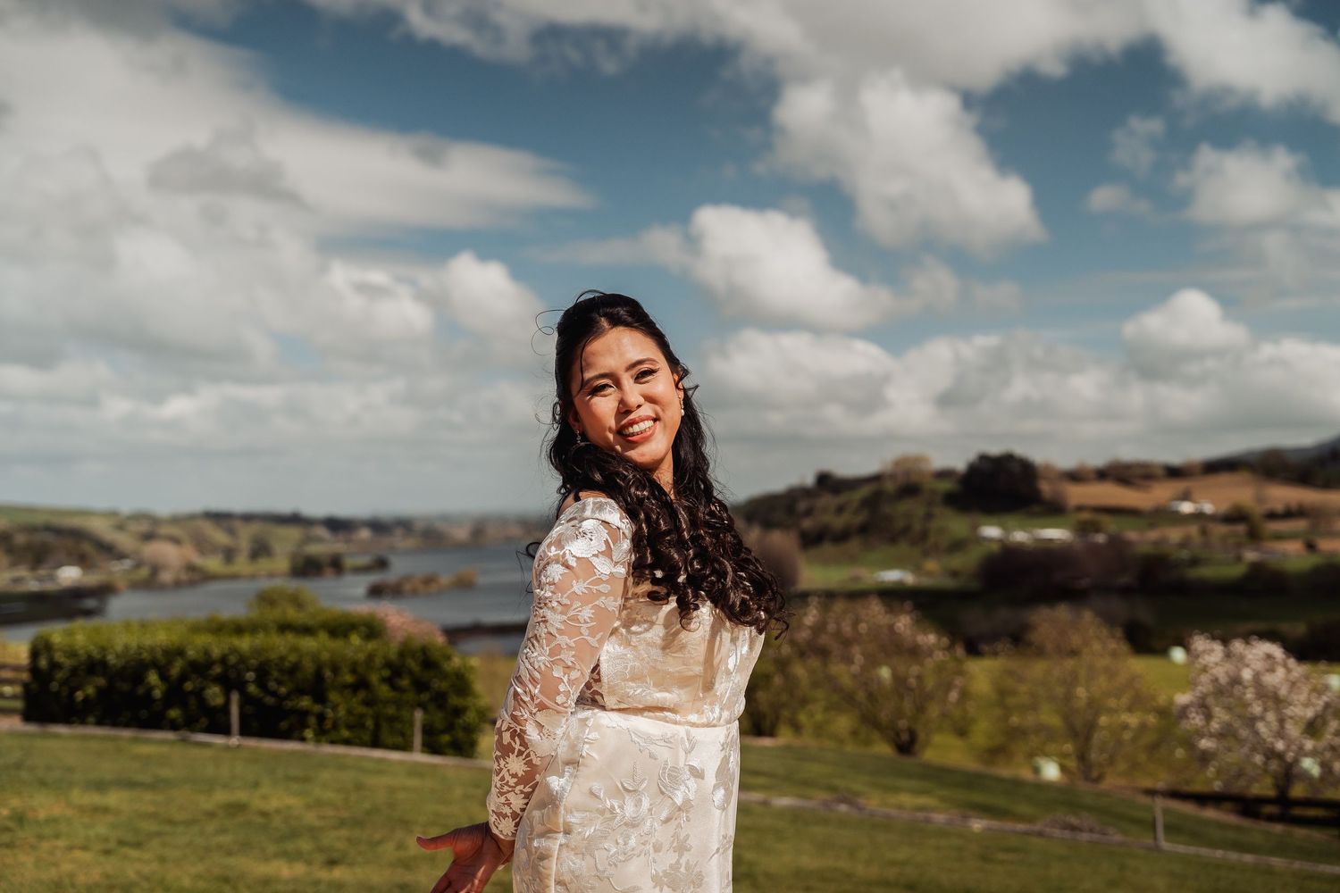 A scenic outdoor wedding venue with rolling hills and cloudy skies in the background.