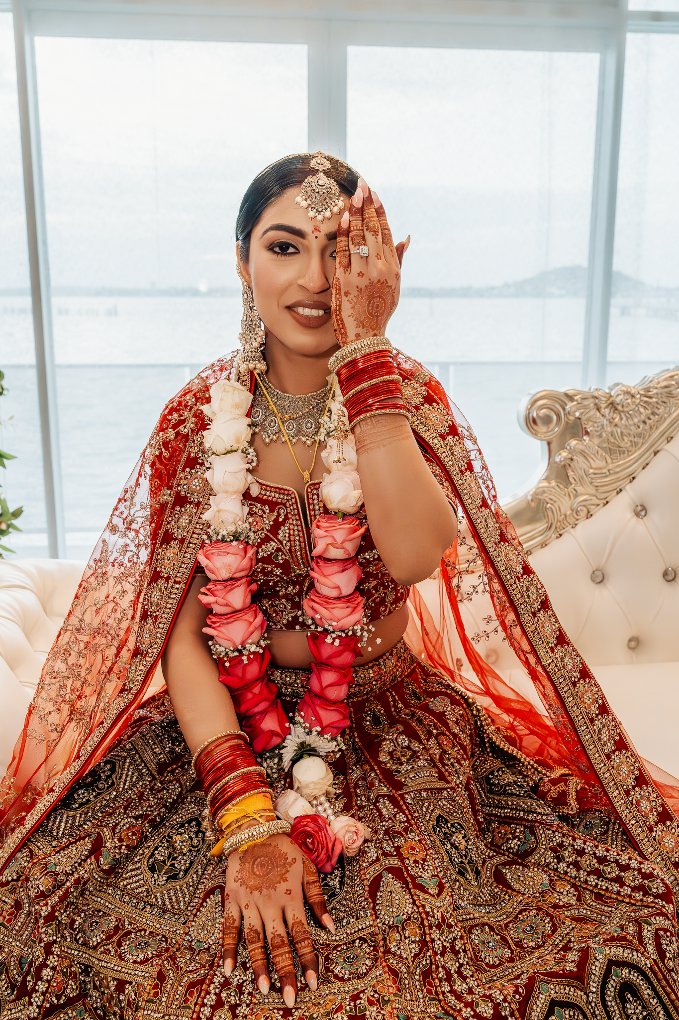 Traditional Indian bride in red lehenga showcasing intricate henna designs and bridal jewelry.