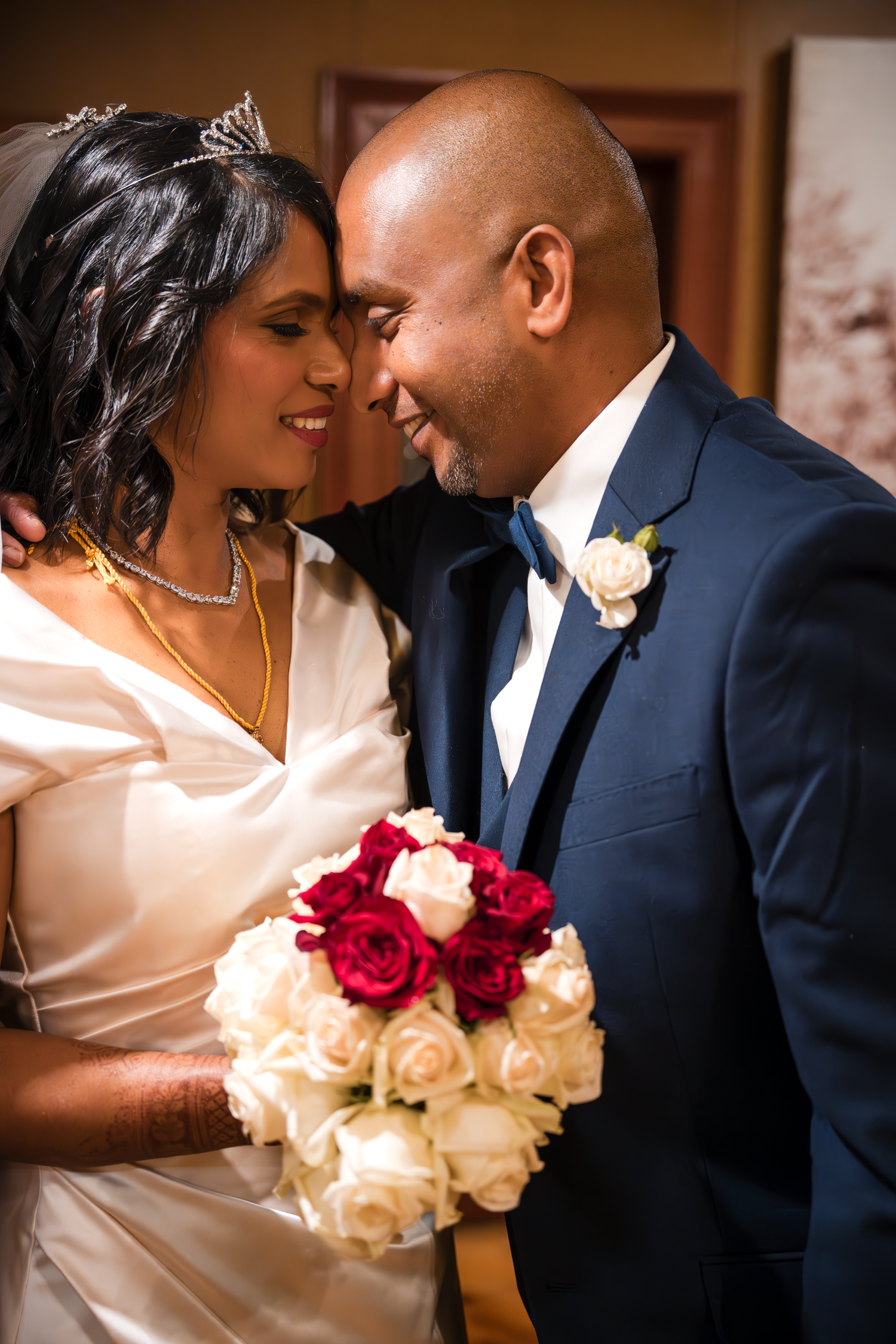 A wedding couple shares a close tender moment while holding a bouquet of mixed roses.