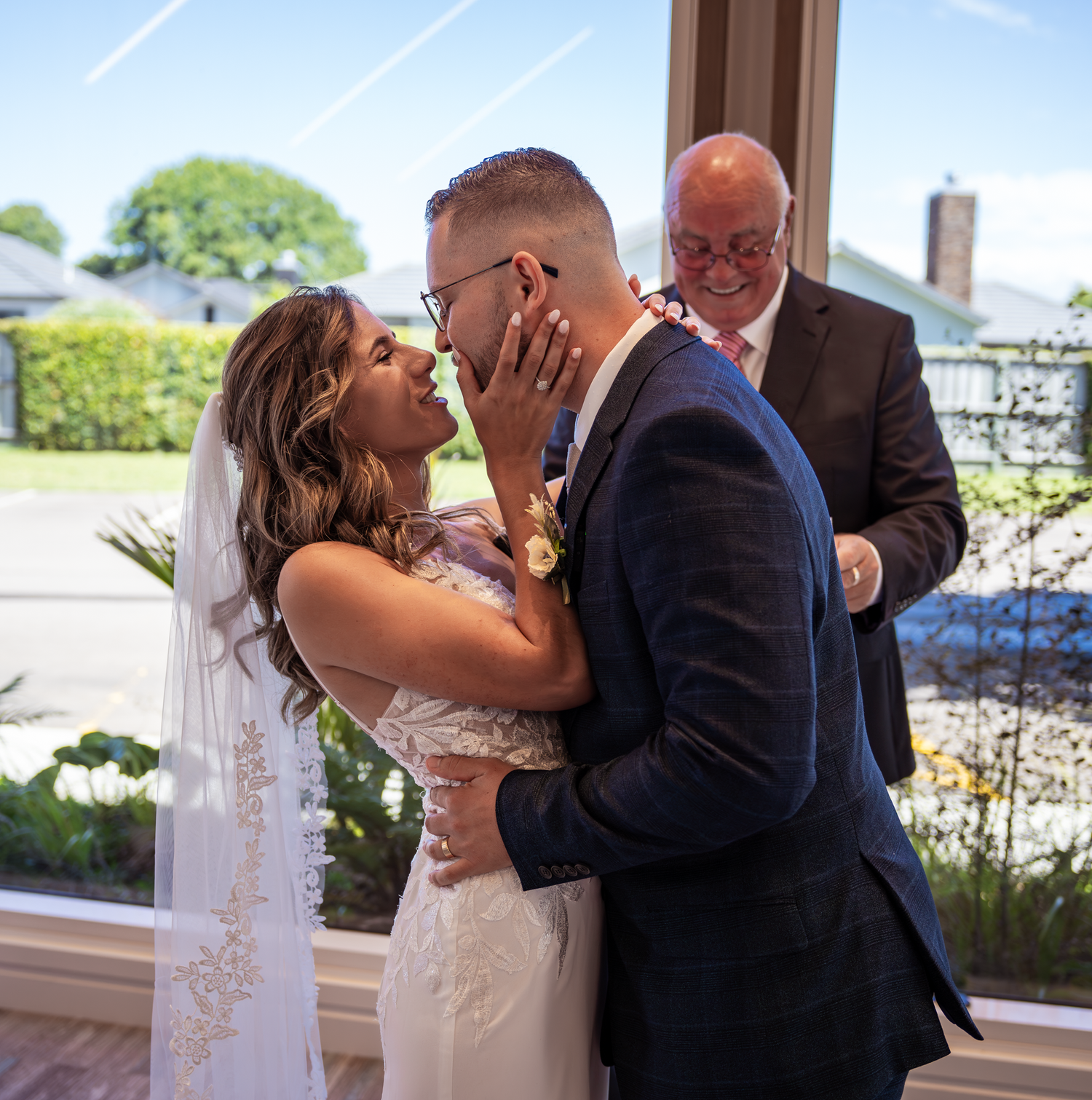An emotional wedding ceremony moment in front of large windows with natural light streaming in.