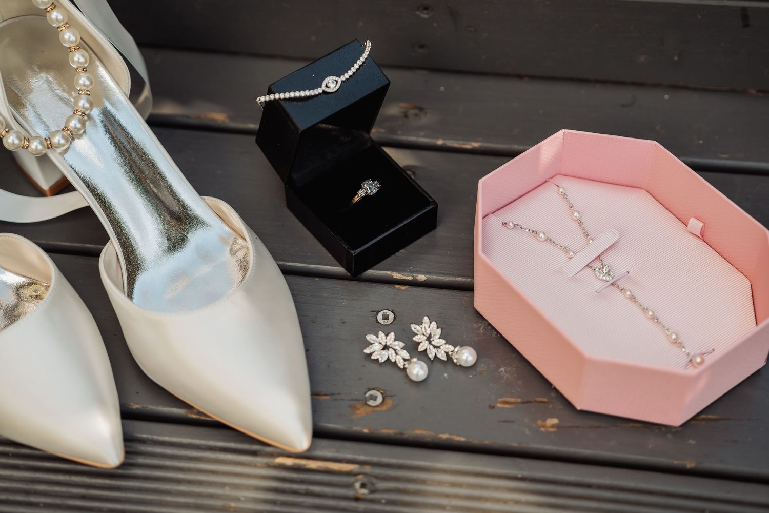 Elegant white and pearl wedding shoes displayed alongside delicate pink and white bridal accessories.