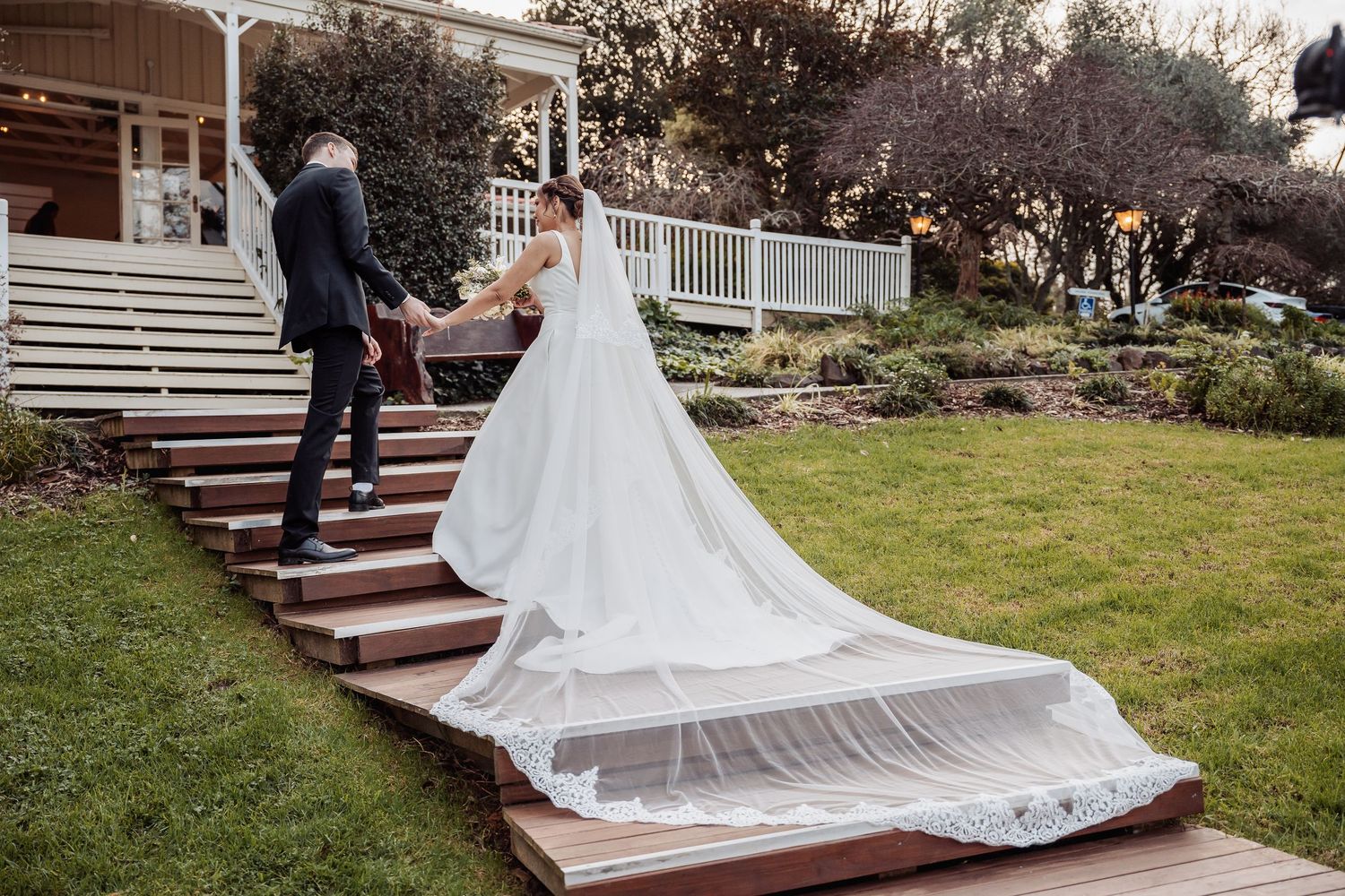 Bride's flowing white dress cascading down wooden steps during wedding portraits.
