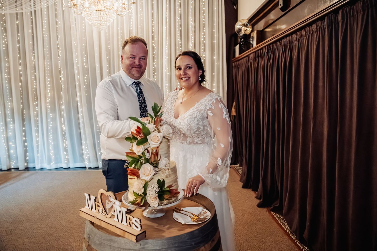 Elegant wedding reception venue with white curtains, chandeliers, and romantic lighting.