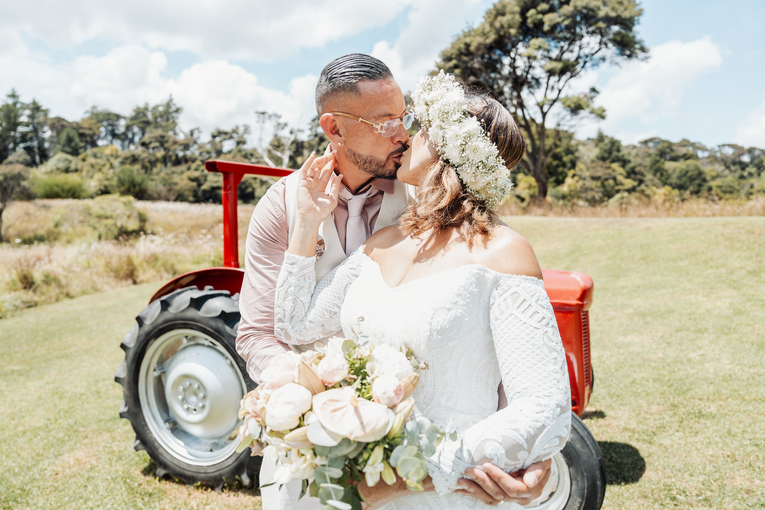 Romantic countryside wedding portrait with a vintage red tractor in the background.