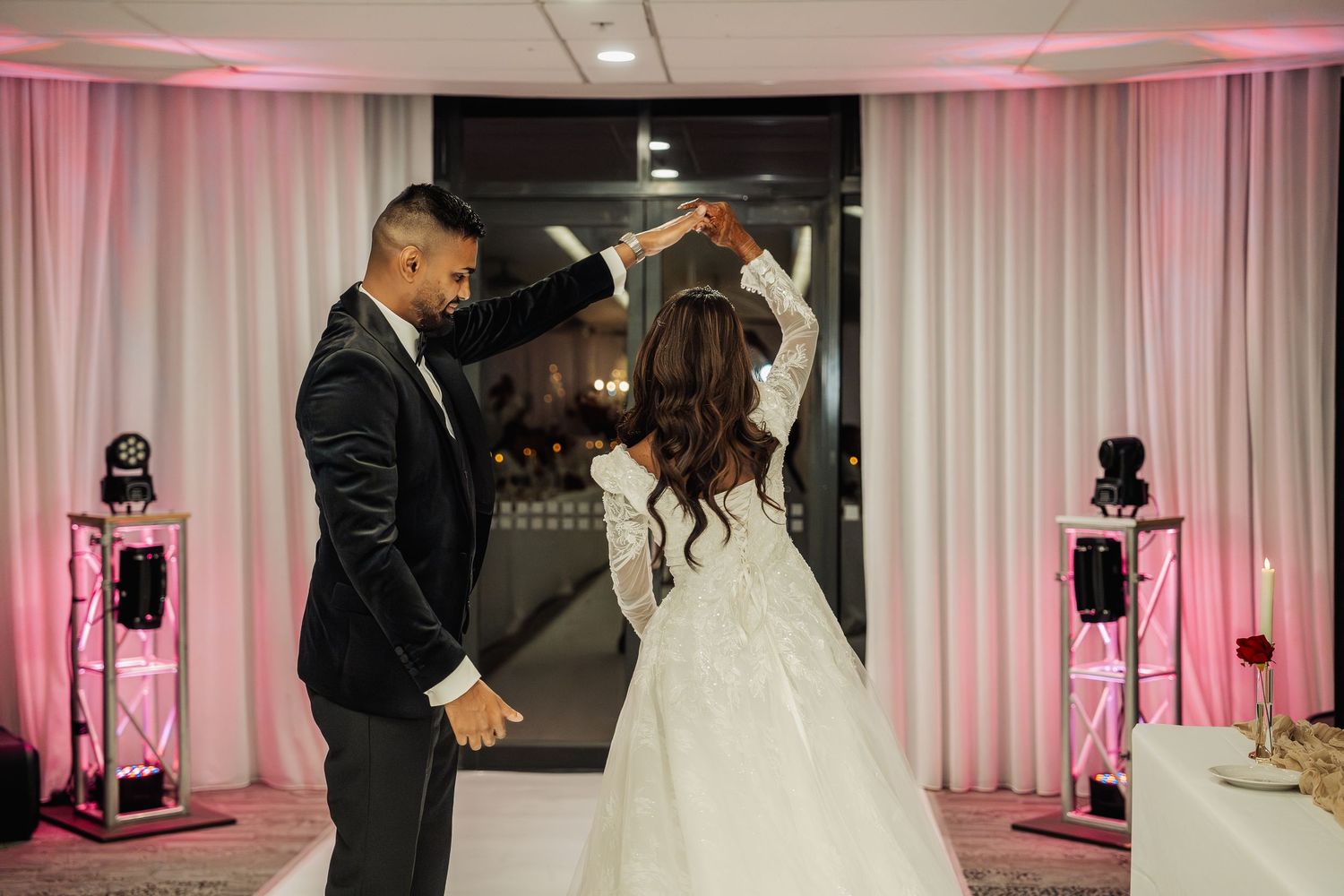 Wedding reception venue with pink uplighting and white drapes creating an elegant atmosphere.