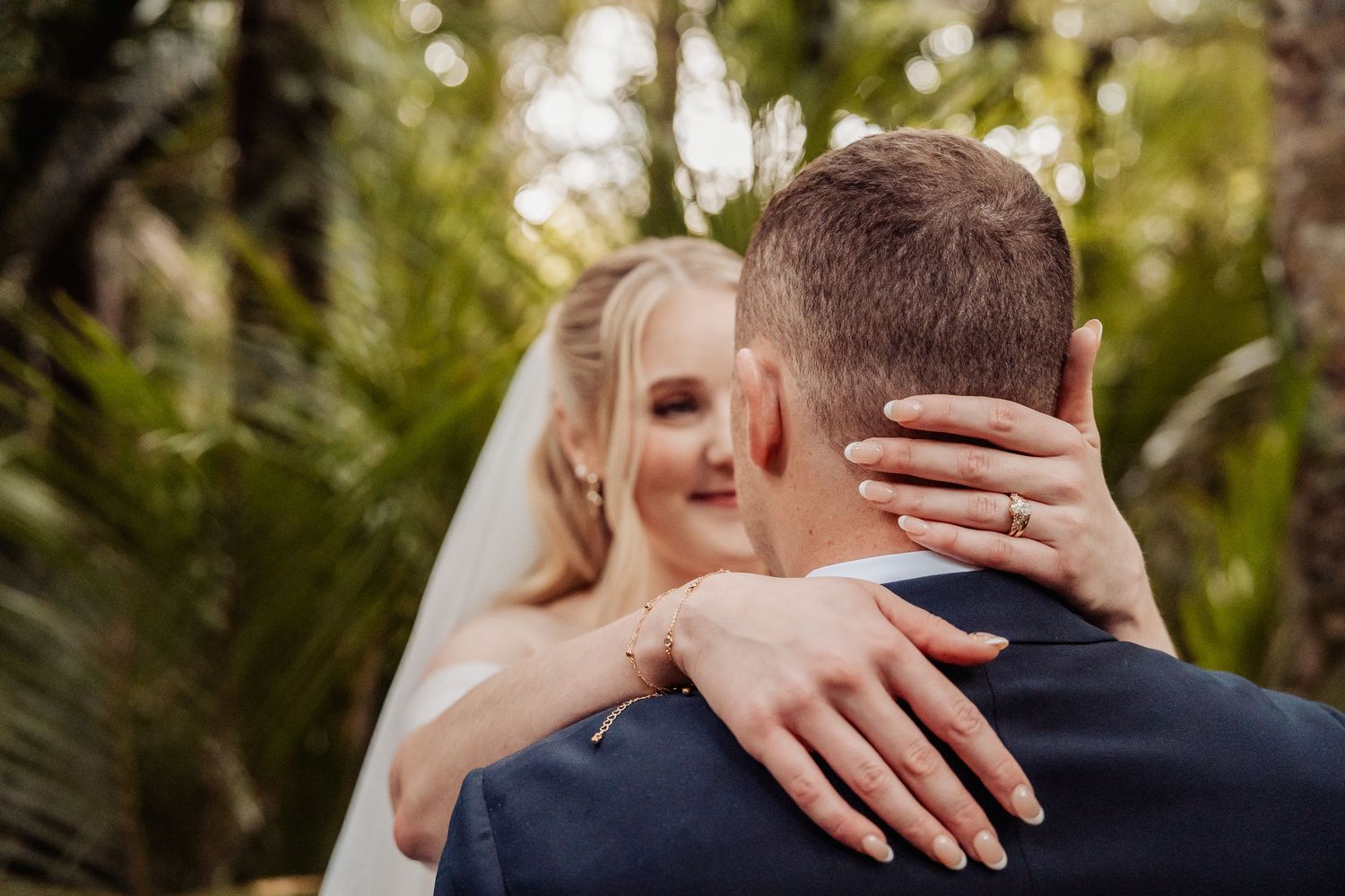 Close-up of newlyweds embracing outdoors with soft natural lighting.