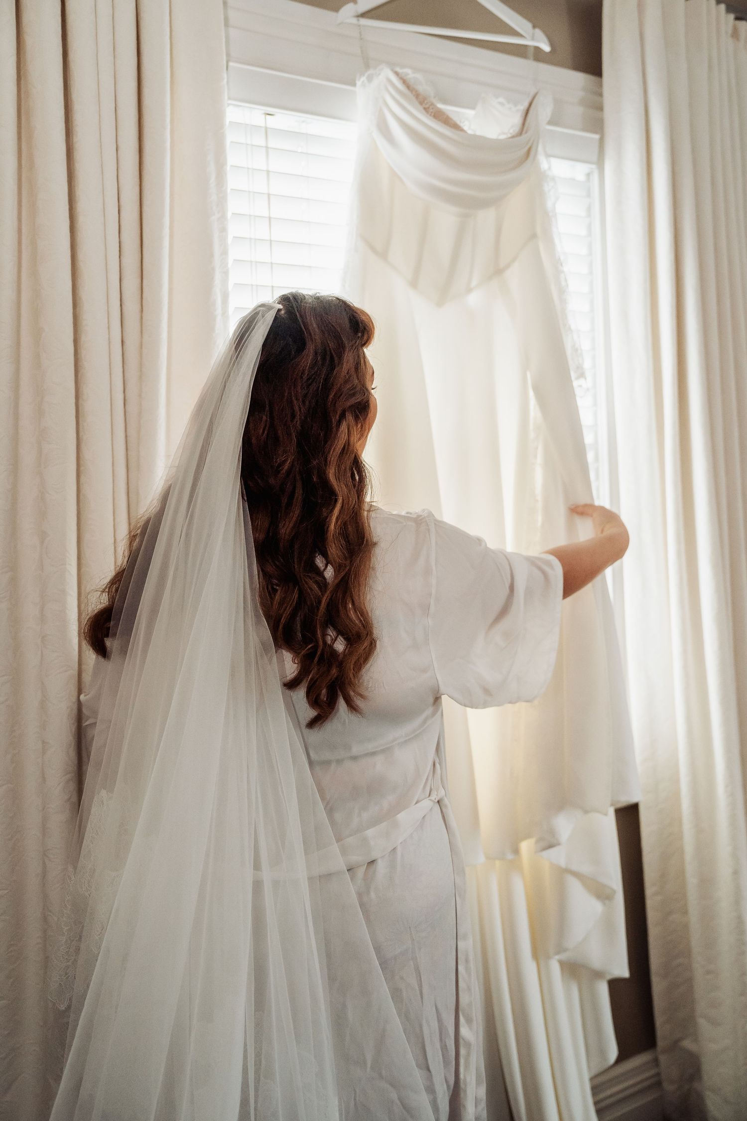 White curtains and sheets hanging on a clothesline in a bright sunlit room create a soft, ethereal atmosphere.