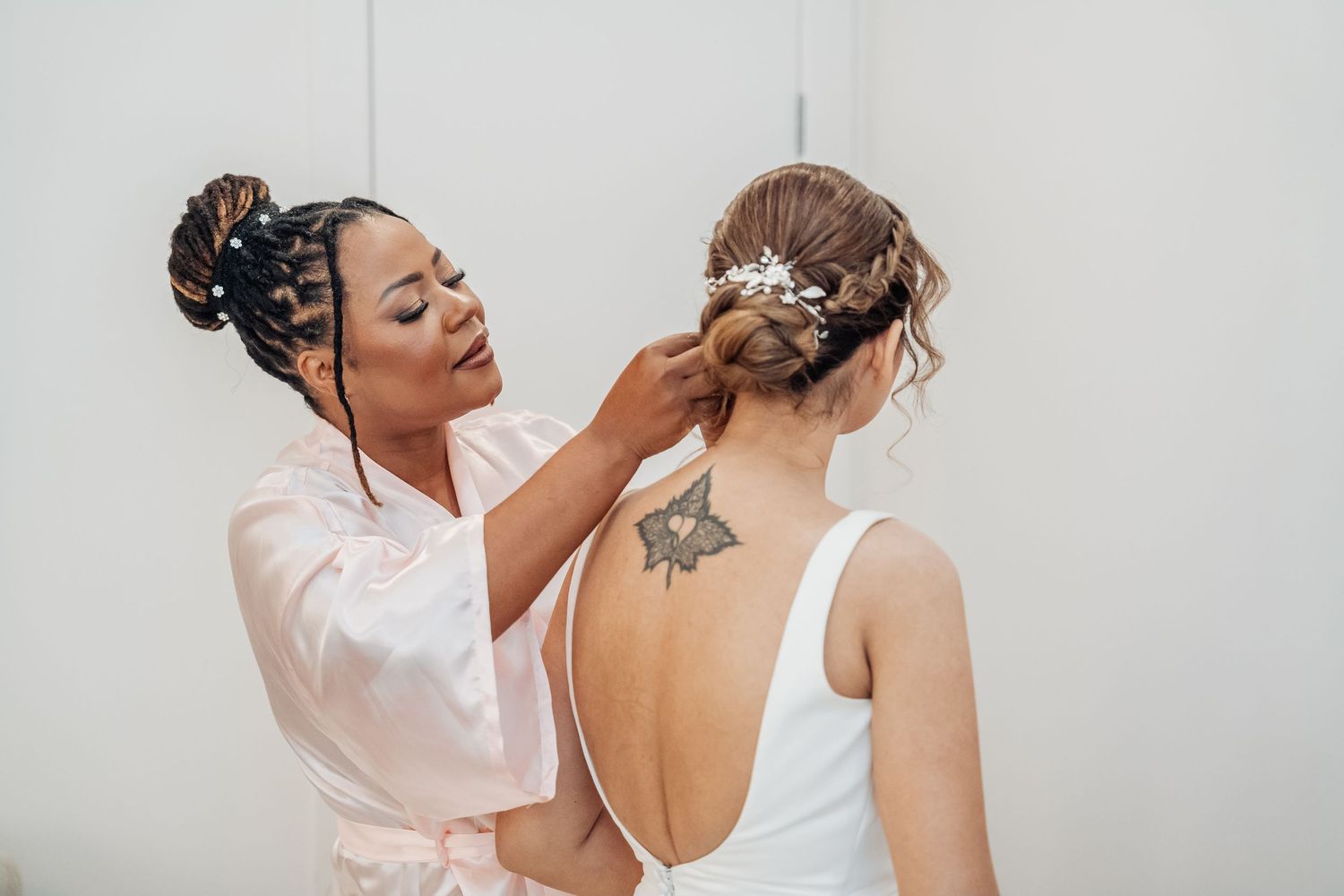 Wedding preparation scene with hairstylist working on styled updo for elegant bridal look.